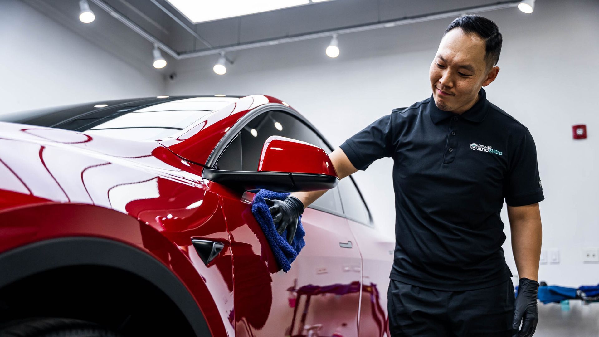 A man is polishing a red car in a garage.