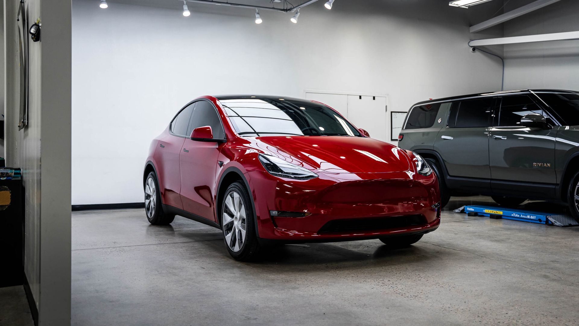 A red tesla model y is parked in a garage.