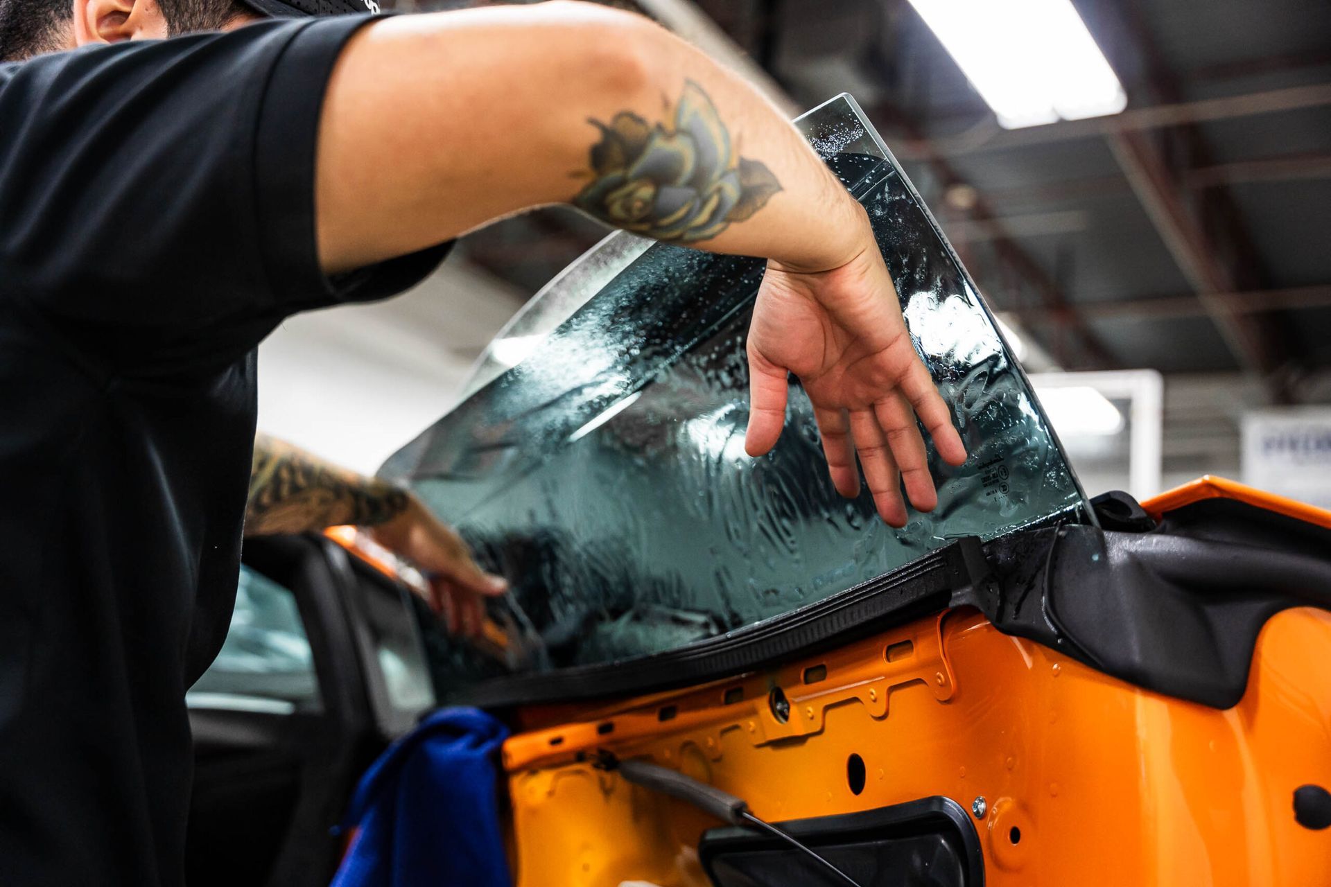 A man is applying tinted glass to a car window.