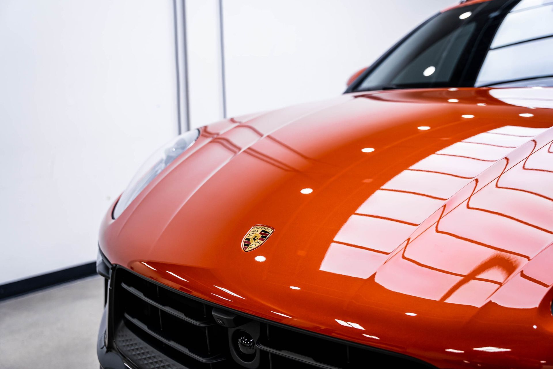 A red porsche macan is parked in a showroom.