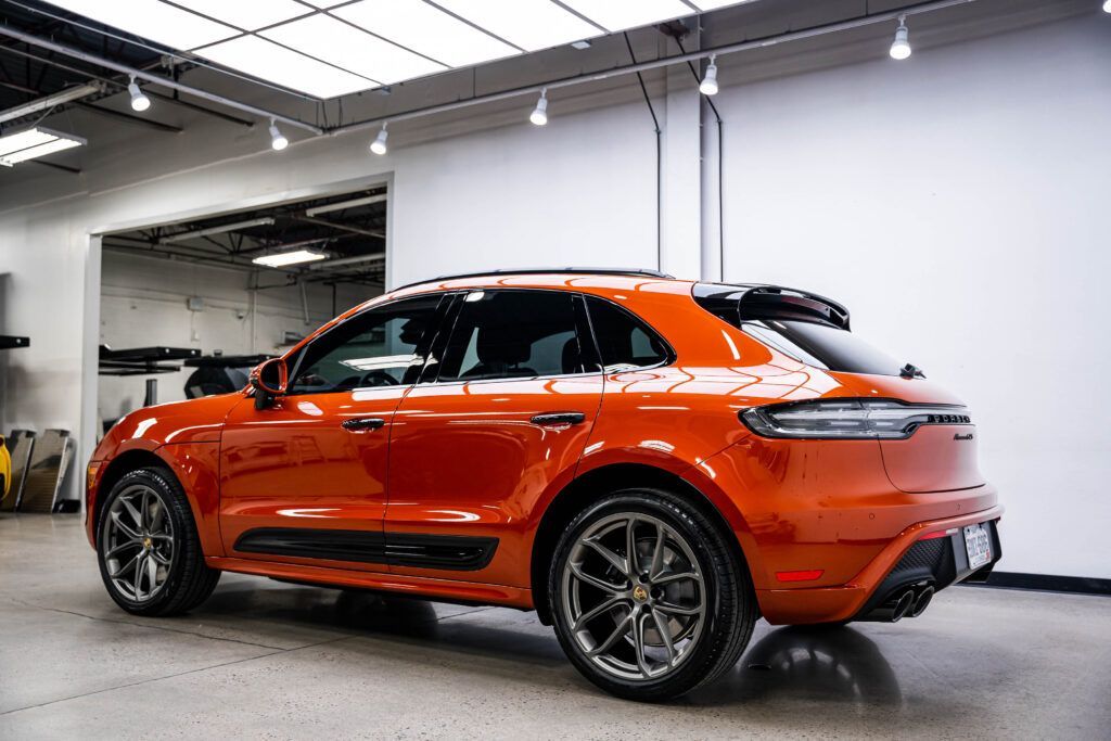 A red porsche macan is parked in a garage.