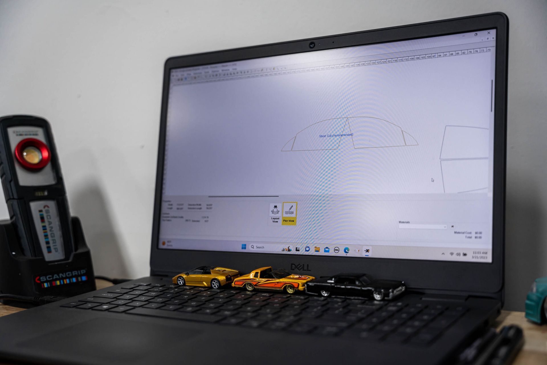 A laptop computer is open to a drawing of a car on the screen.