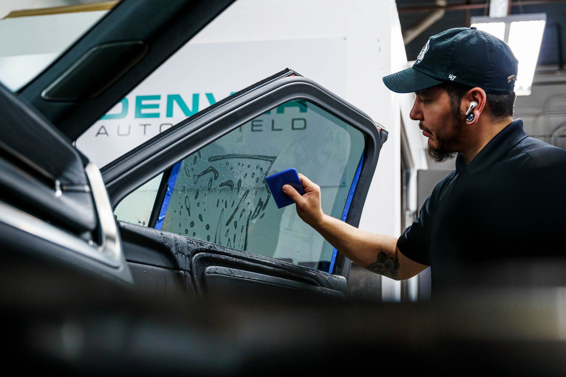 A man is applying window tinting to a car window.