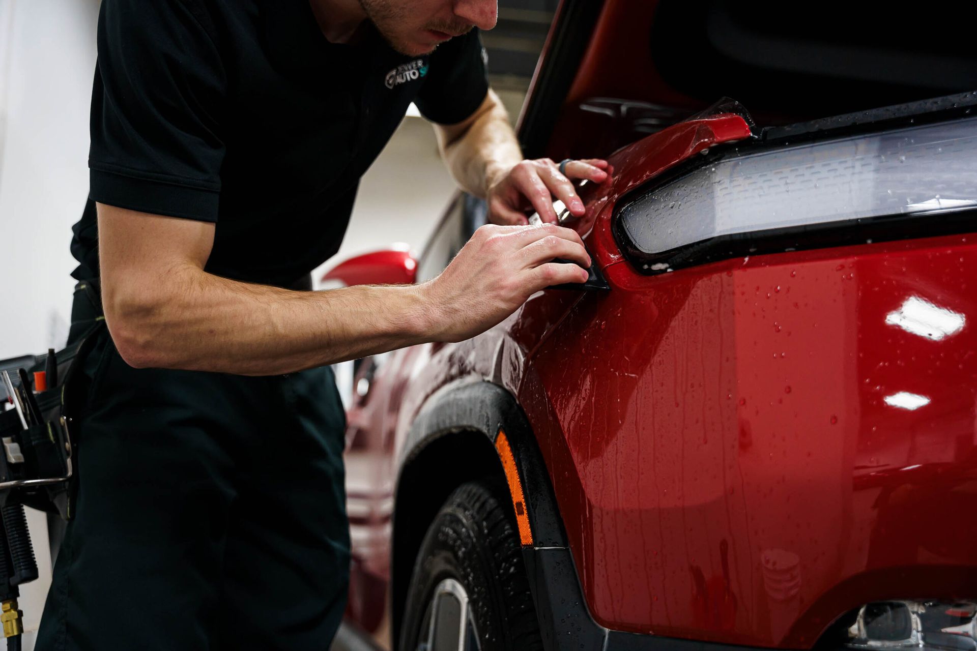 A man is working on a red car in a garage.