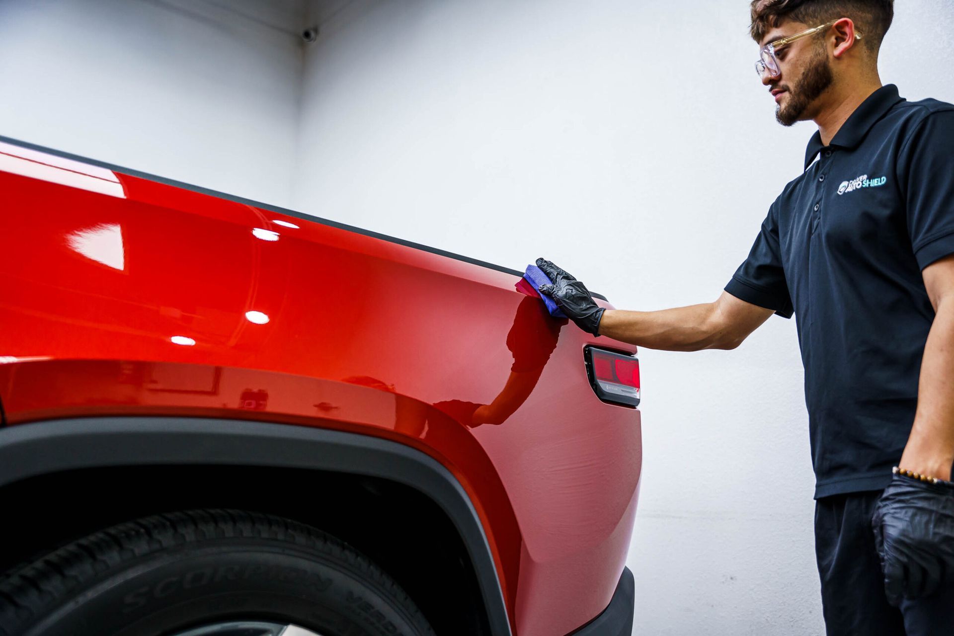 A man is cleaning the back of a red truck.