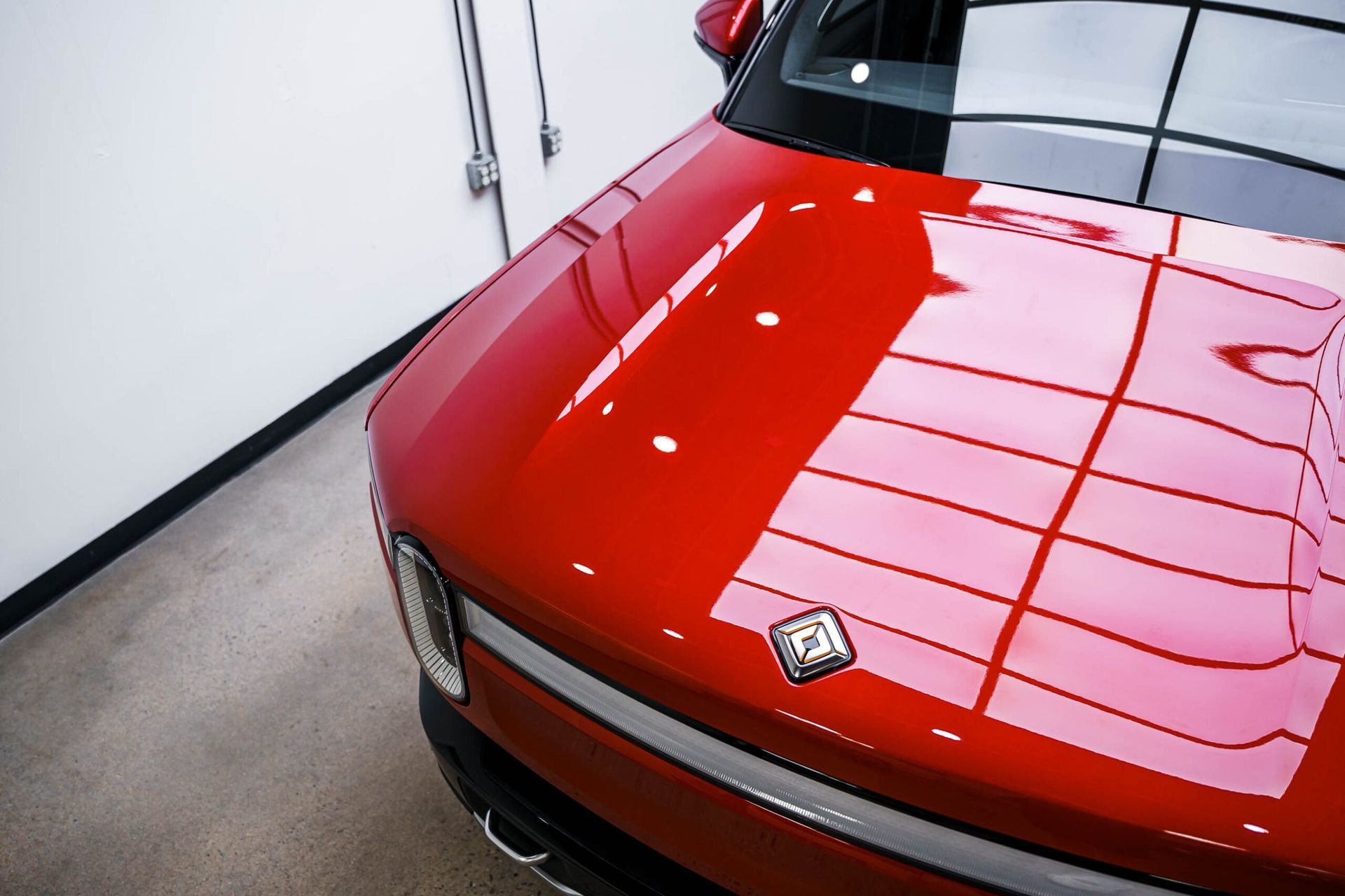 A red car is parked in a garage with the hood up