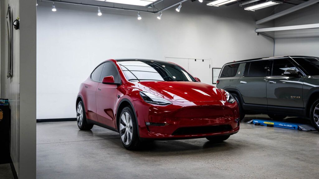 A red tesla model y is parked in a garage.