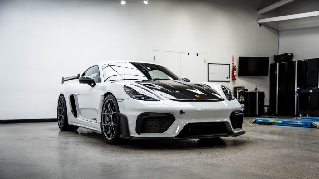 A white sports car is parked in a garage.