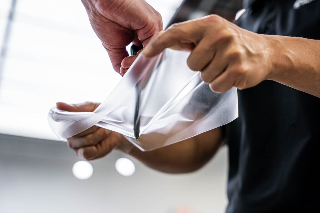 A man is cutting a piece of plastic with scissors.