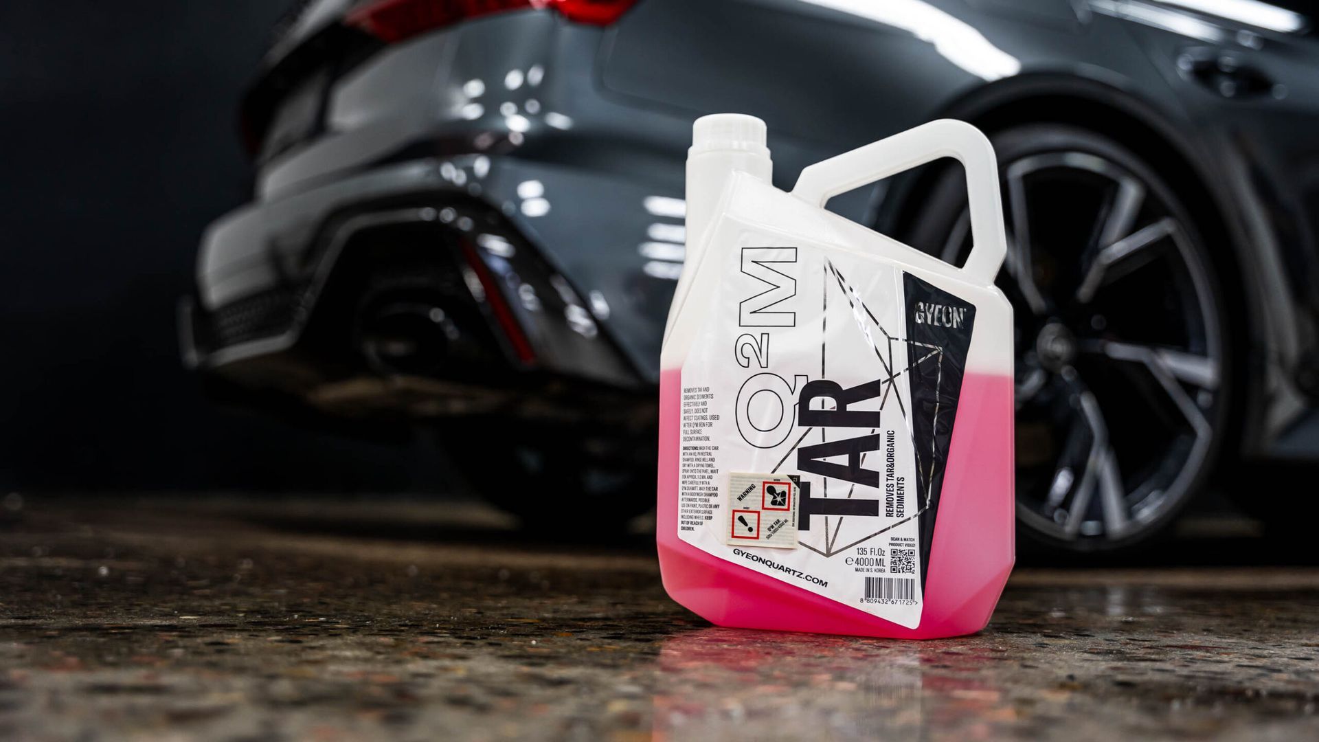 A bottle of foam is sitting in front of a car.