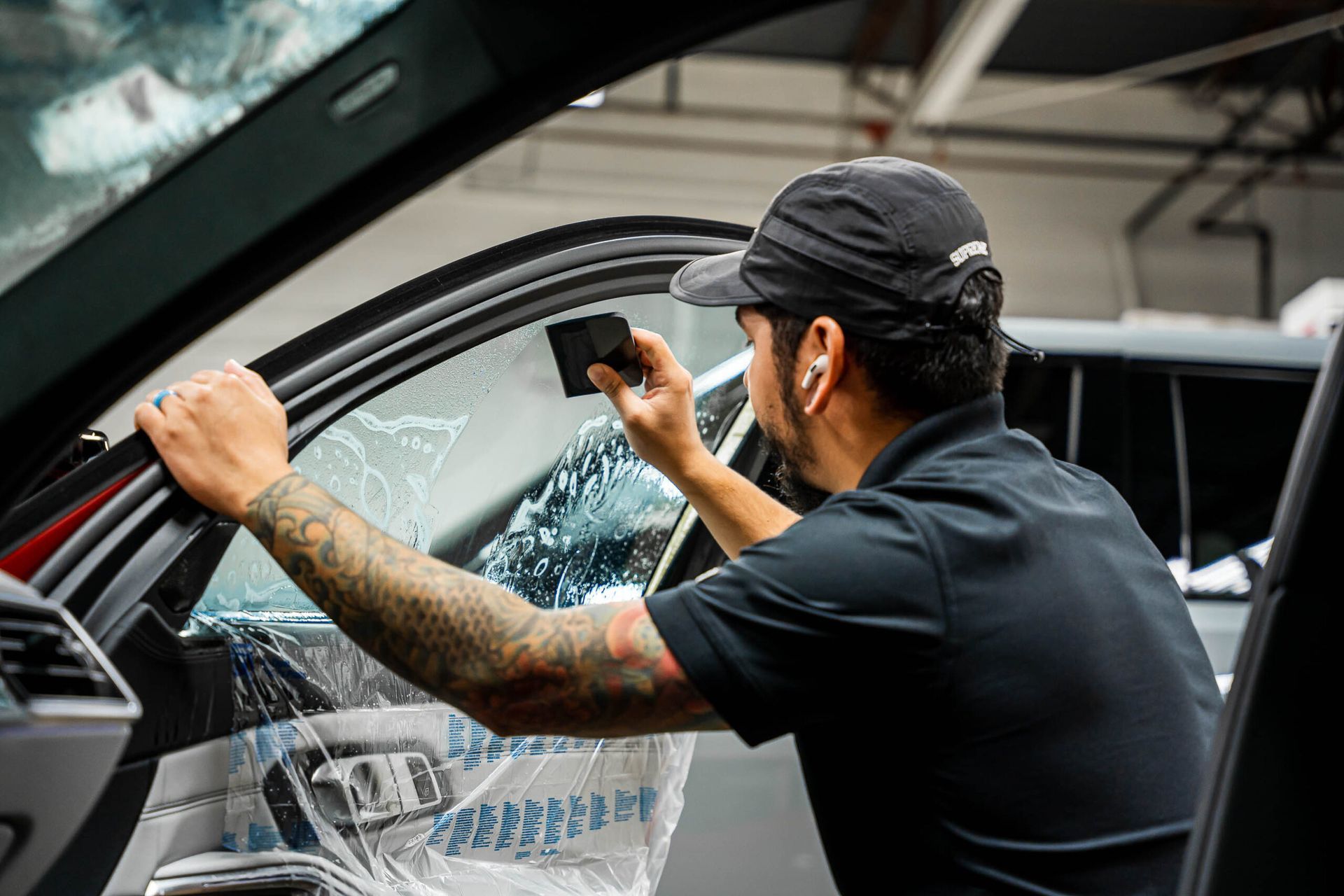 A man is applying window tinting to a car window.