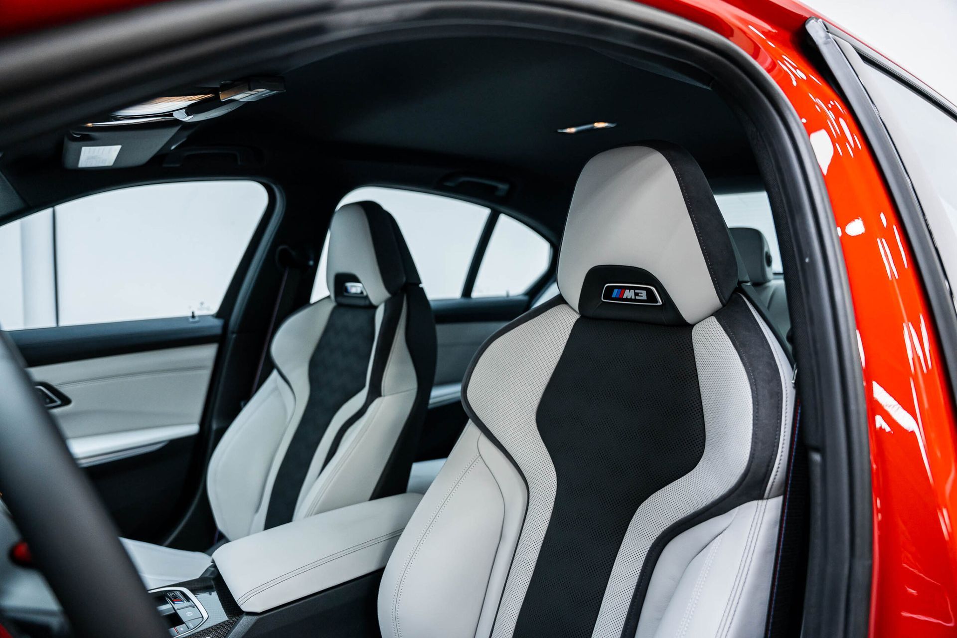 The interior of a red car with black and white seats.