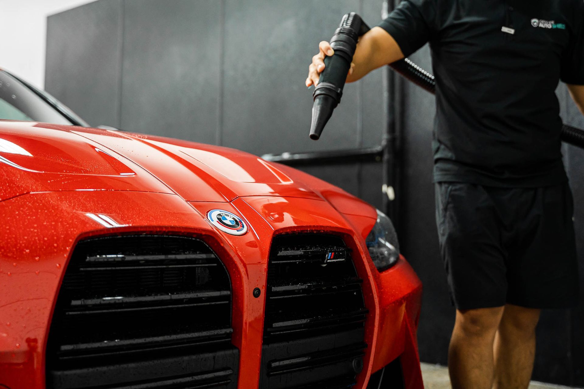 A man is drying a red car with a blow dryer.