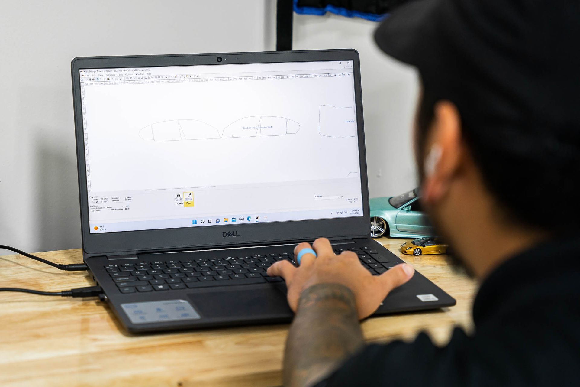 A man is typing on a laptop computer on a wooden table.