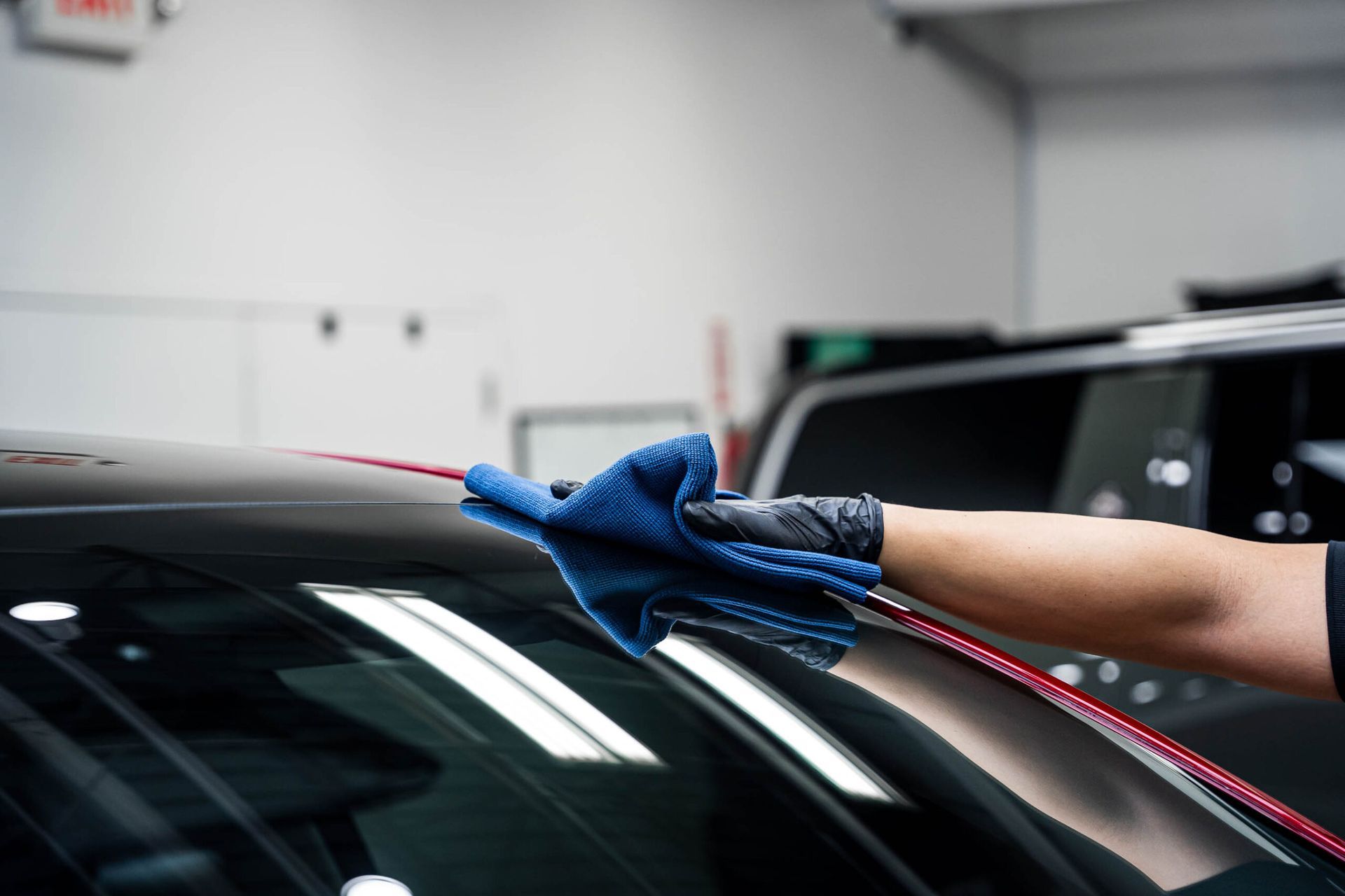 A person is cleaning the windshield of a car with a blue cloth.