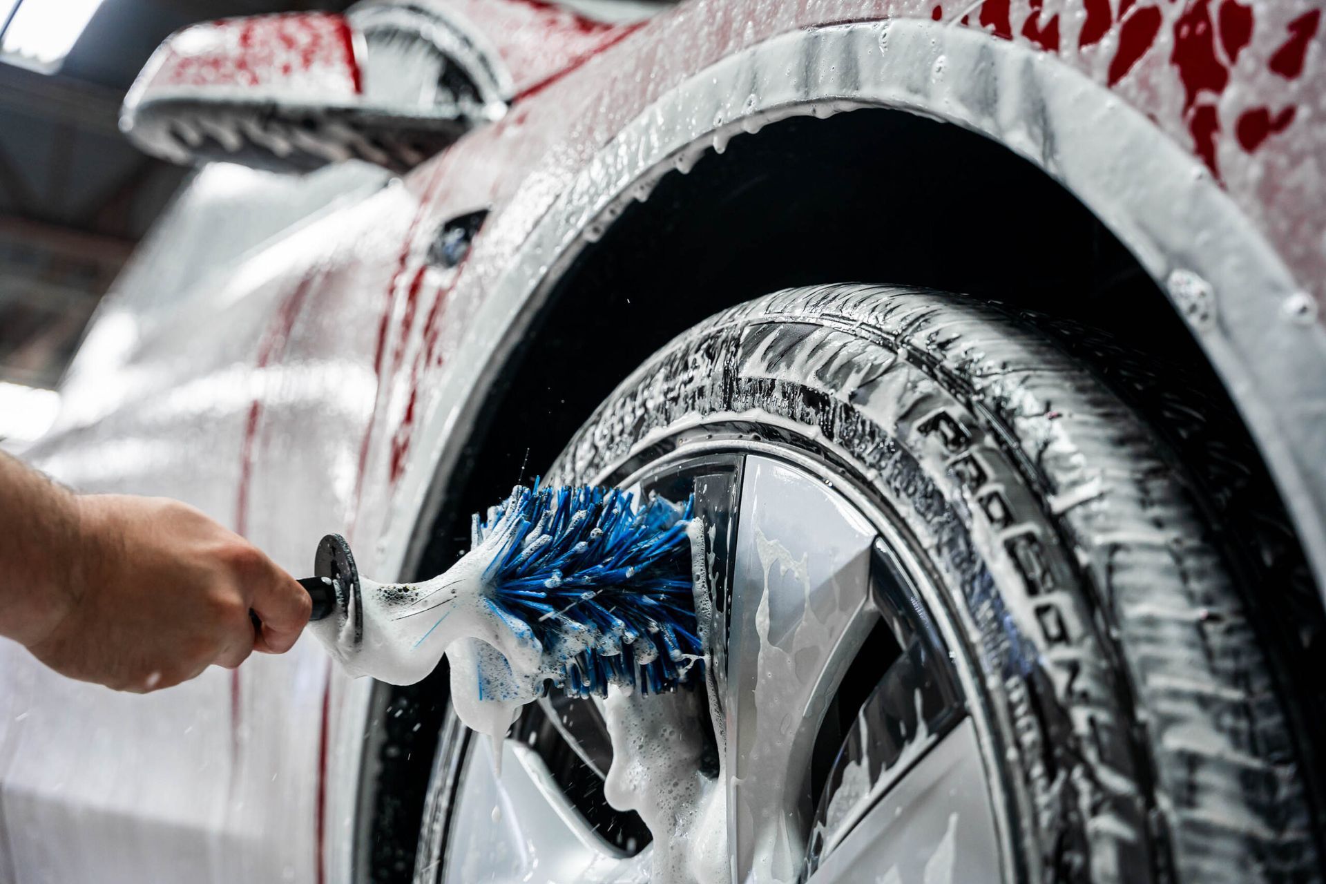 A person is cleaning a car wheel with a brush.