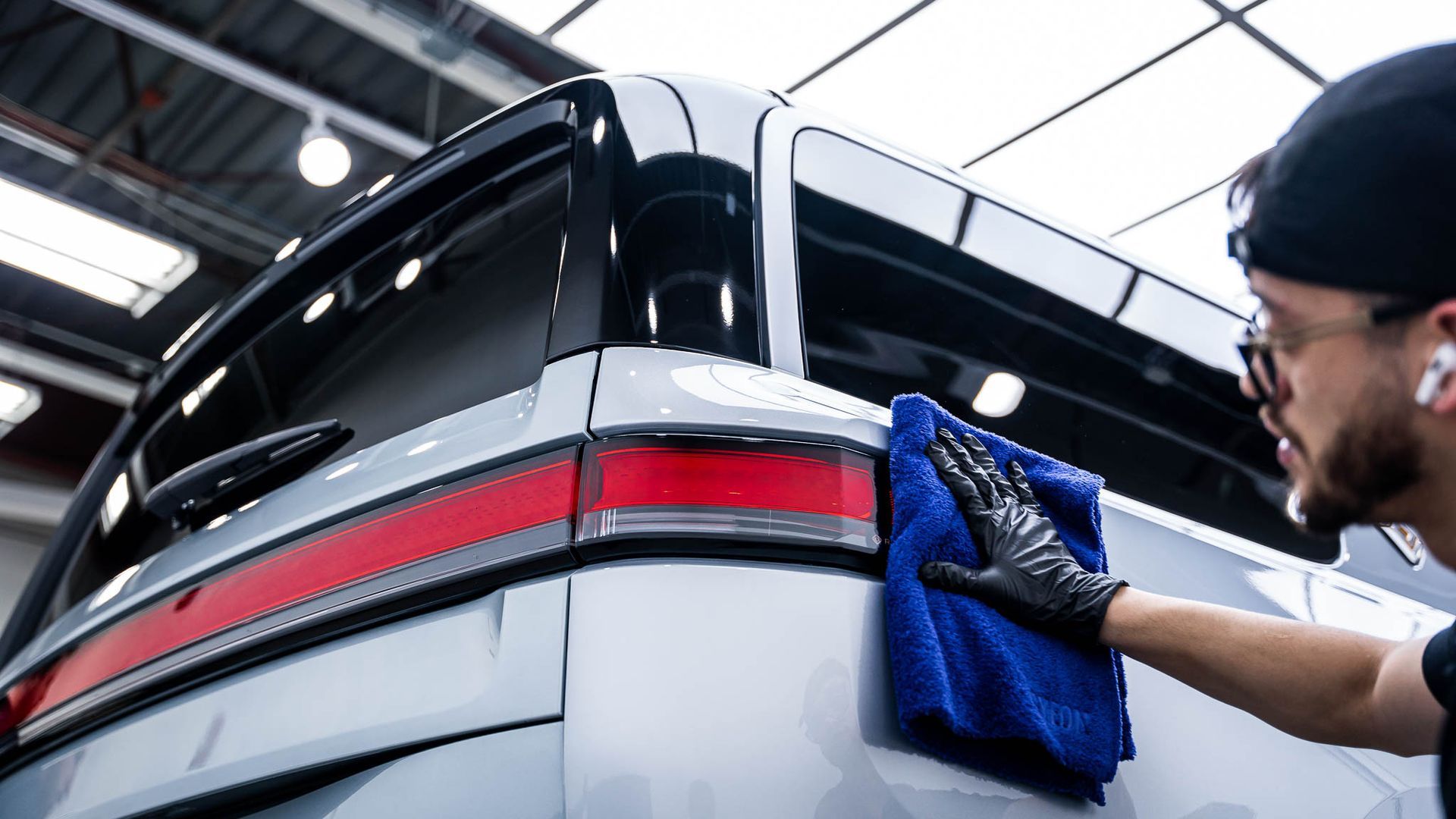 A man is cleaning a car with a towel in a garage.