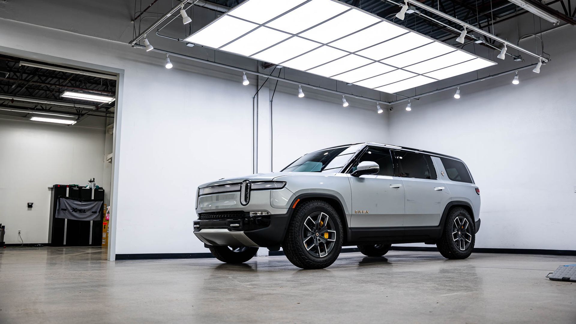 A silver suv is parked in a garage under a ceiling light.