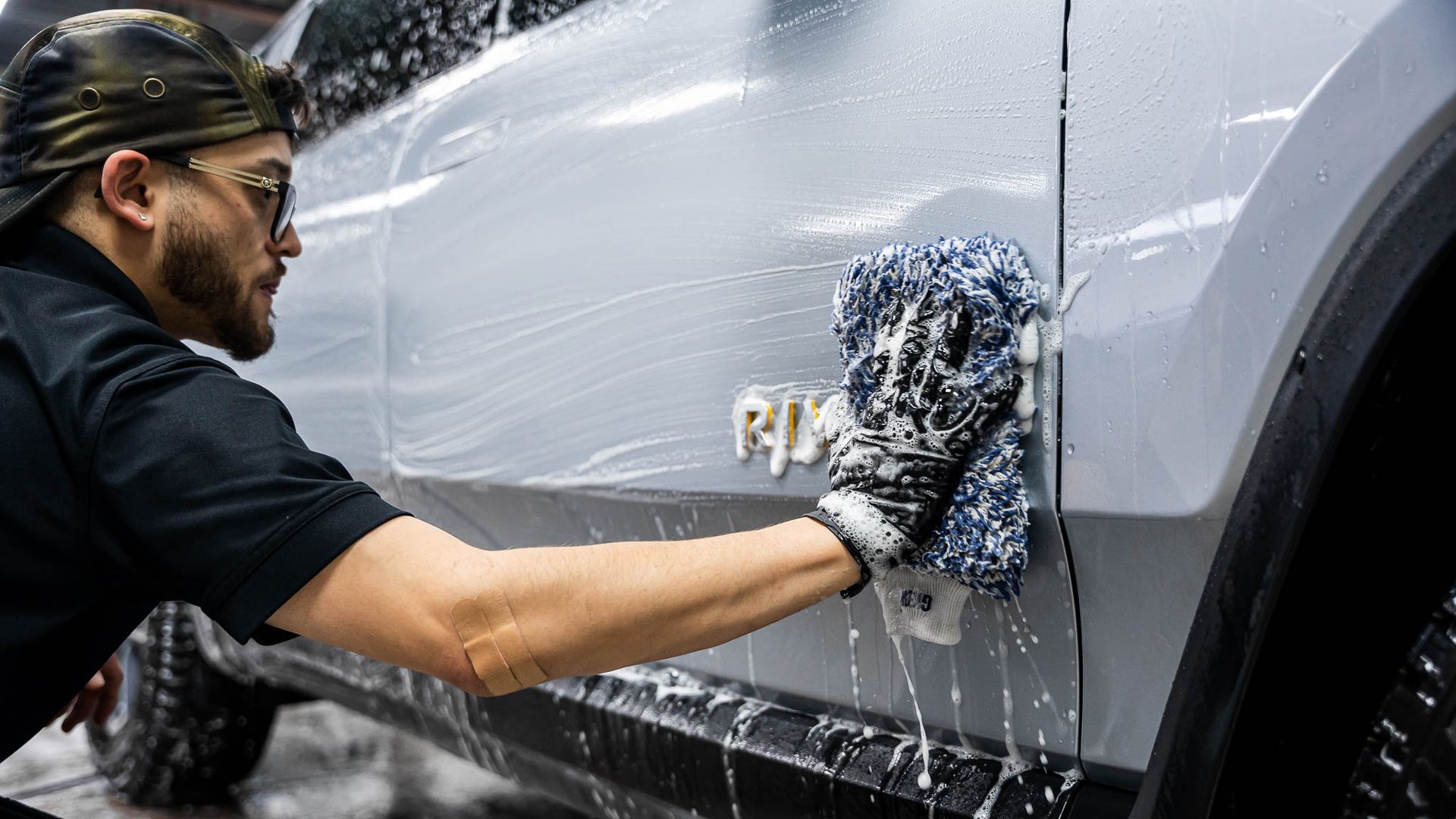 A man is washing a car with a cloth and soap.