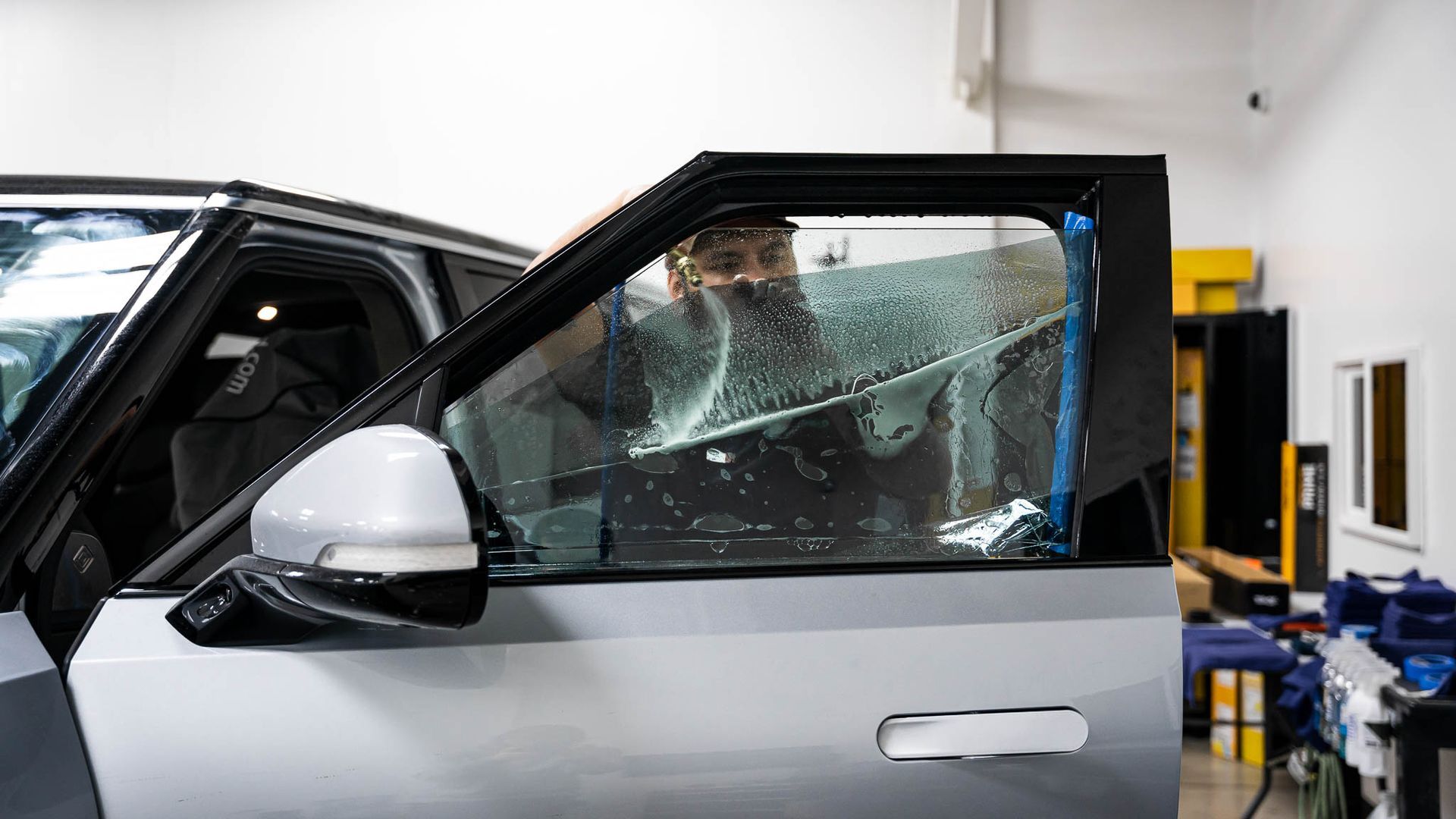 A man is covering a car window with a film.