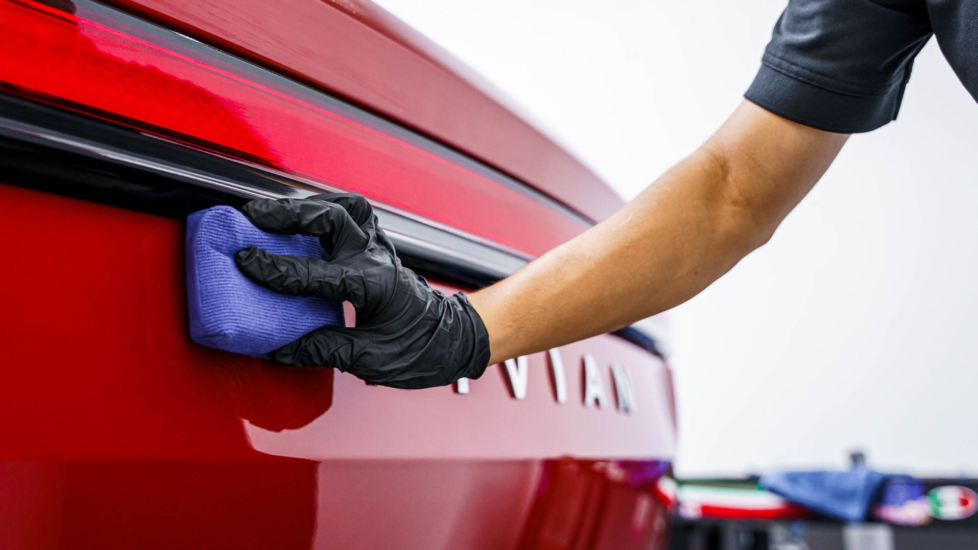 A person is cleaning a red car with a sponge.