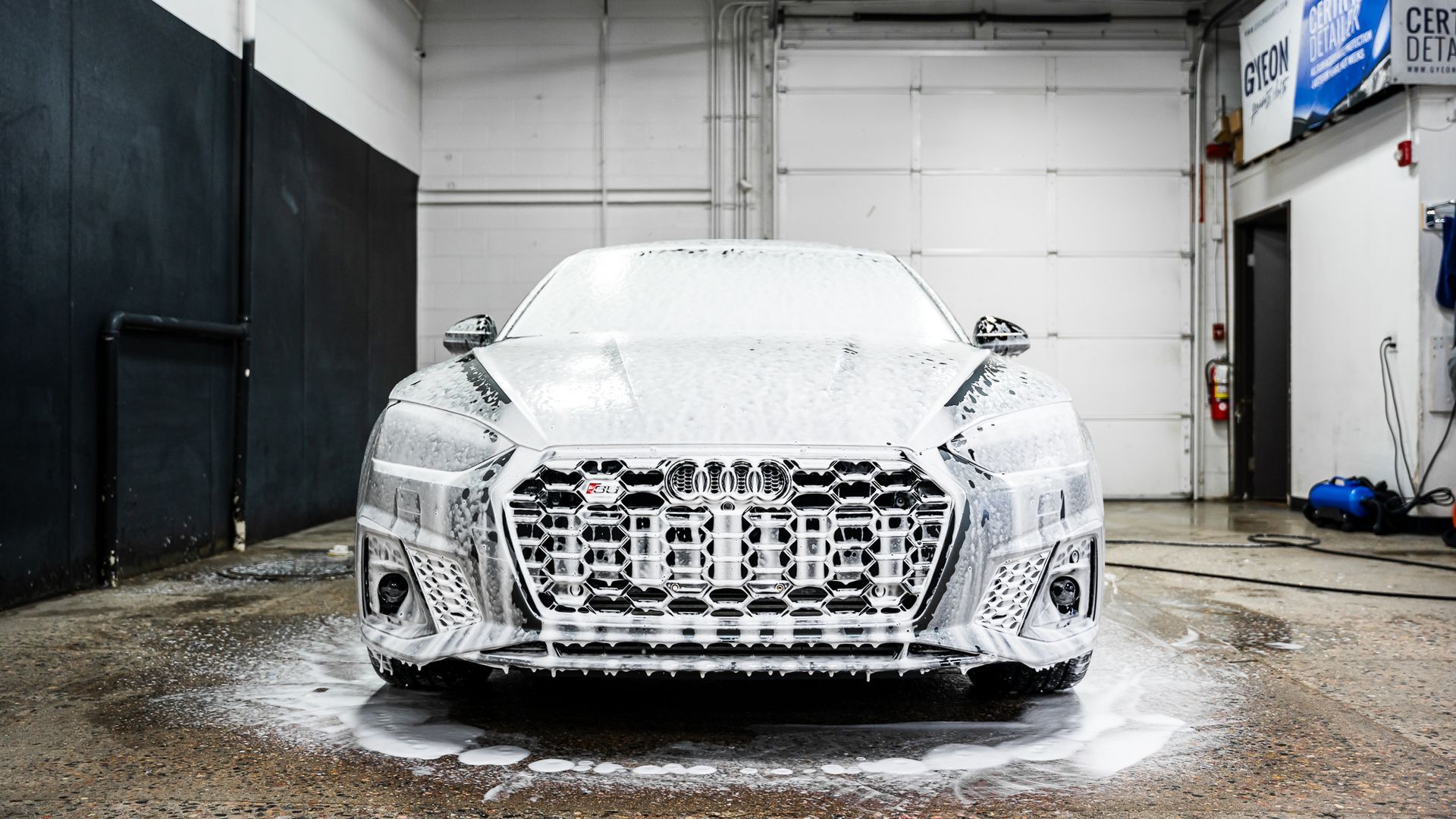 A car is covered in foam in a garage.