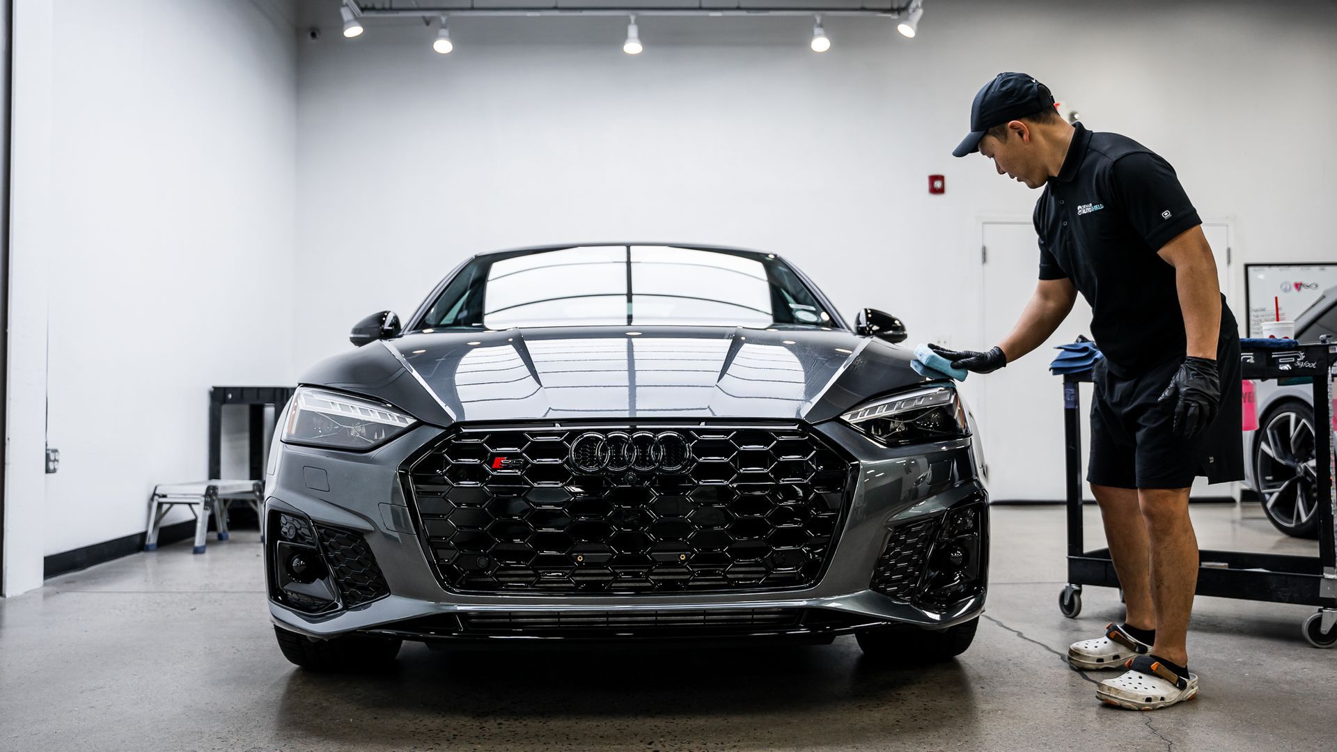 A man is cleaning a car in a garage.