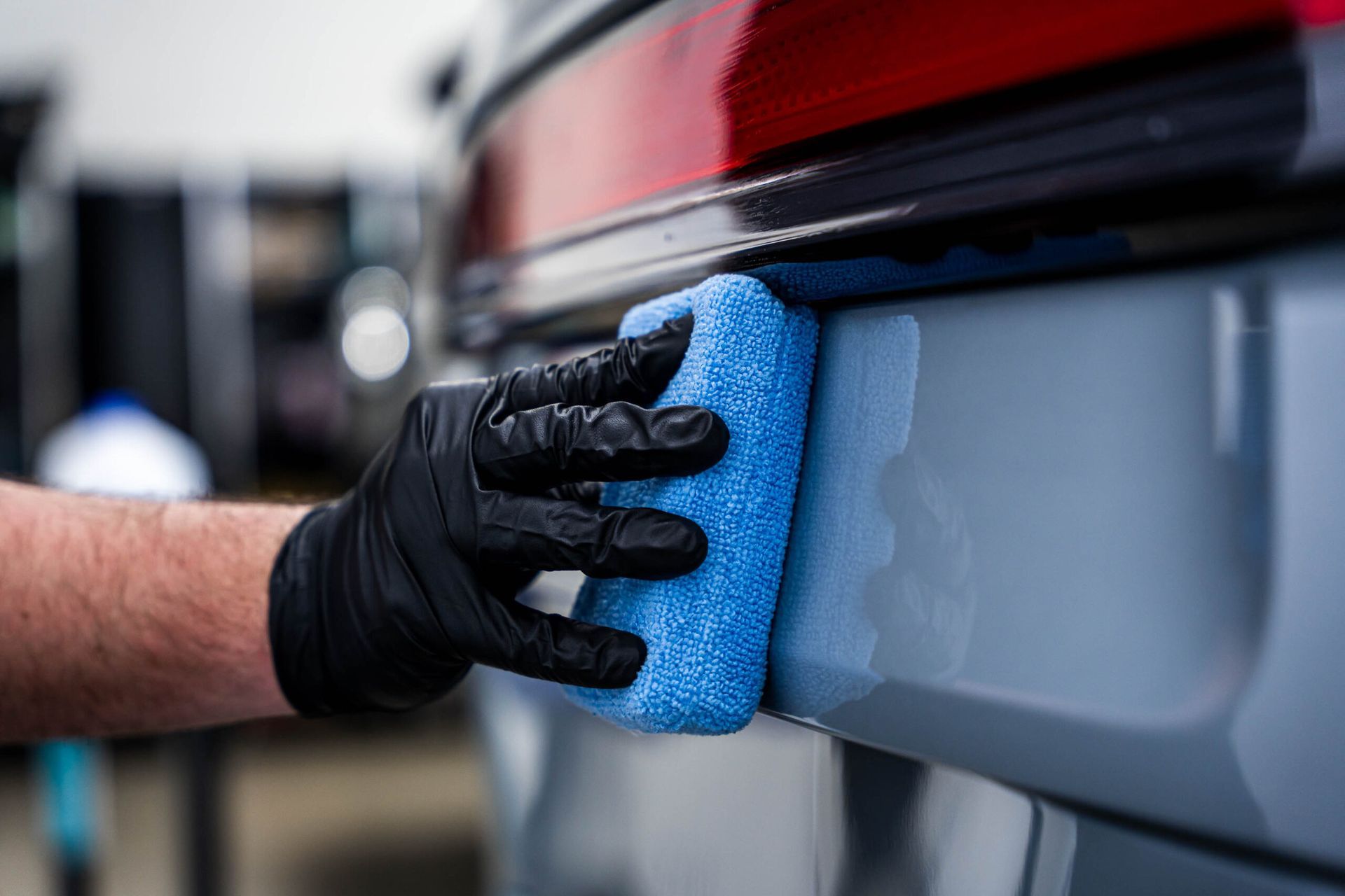 A person is cleaning a car with a blue sponge.