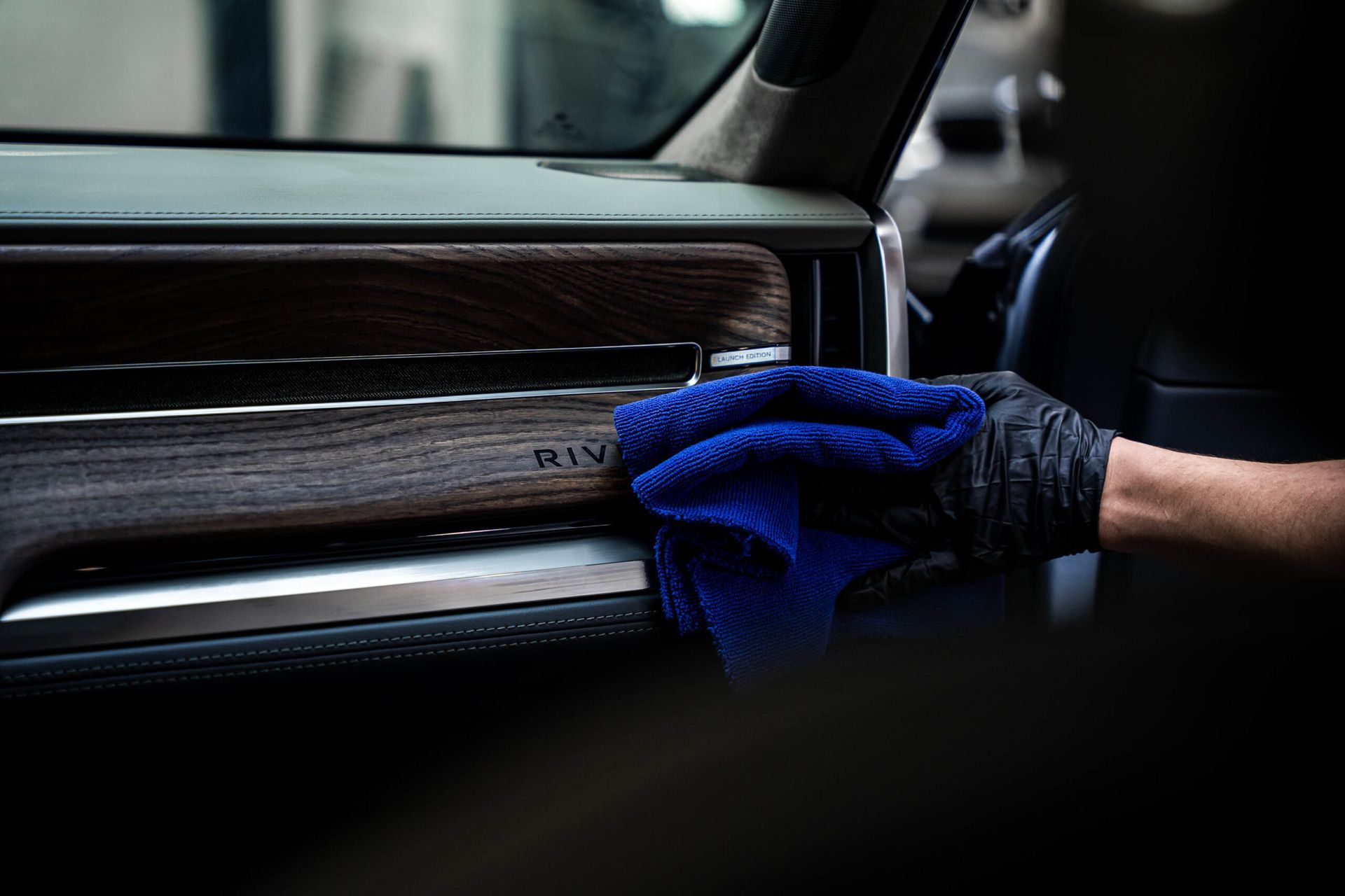 A person is cleaning the interior of a car with a blue towel.