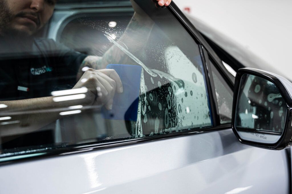 A man is applying window tinting to a car window.