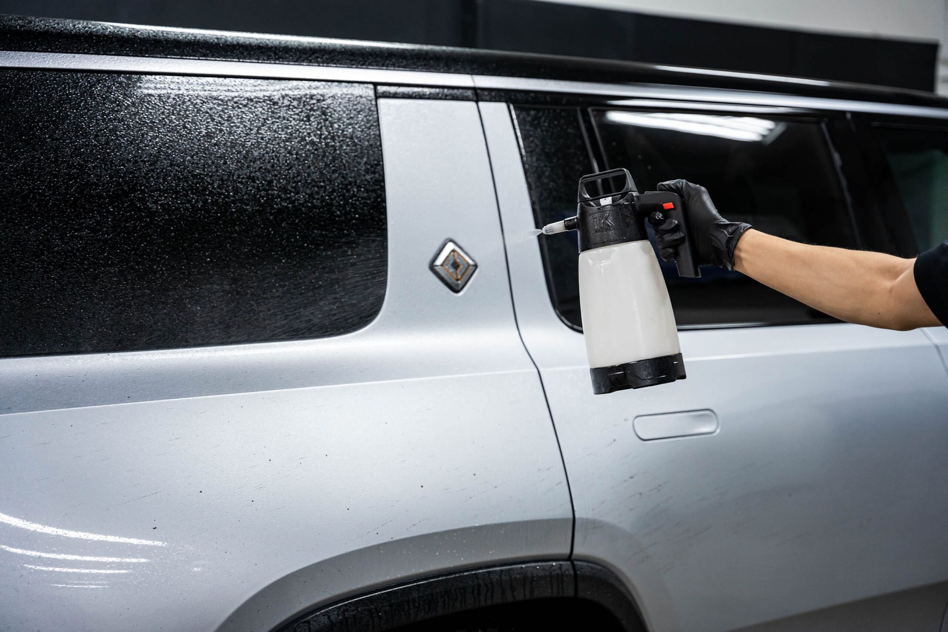 A person is spraying a car with a spray bottle.