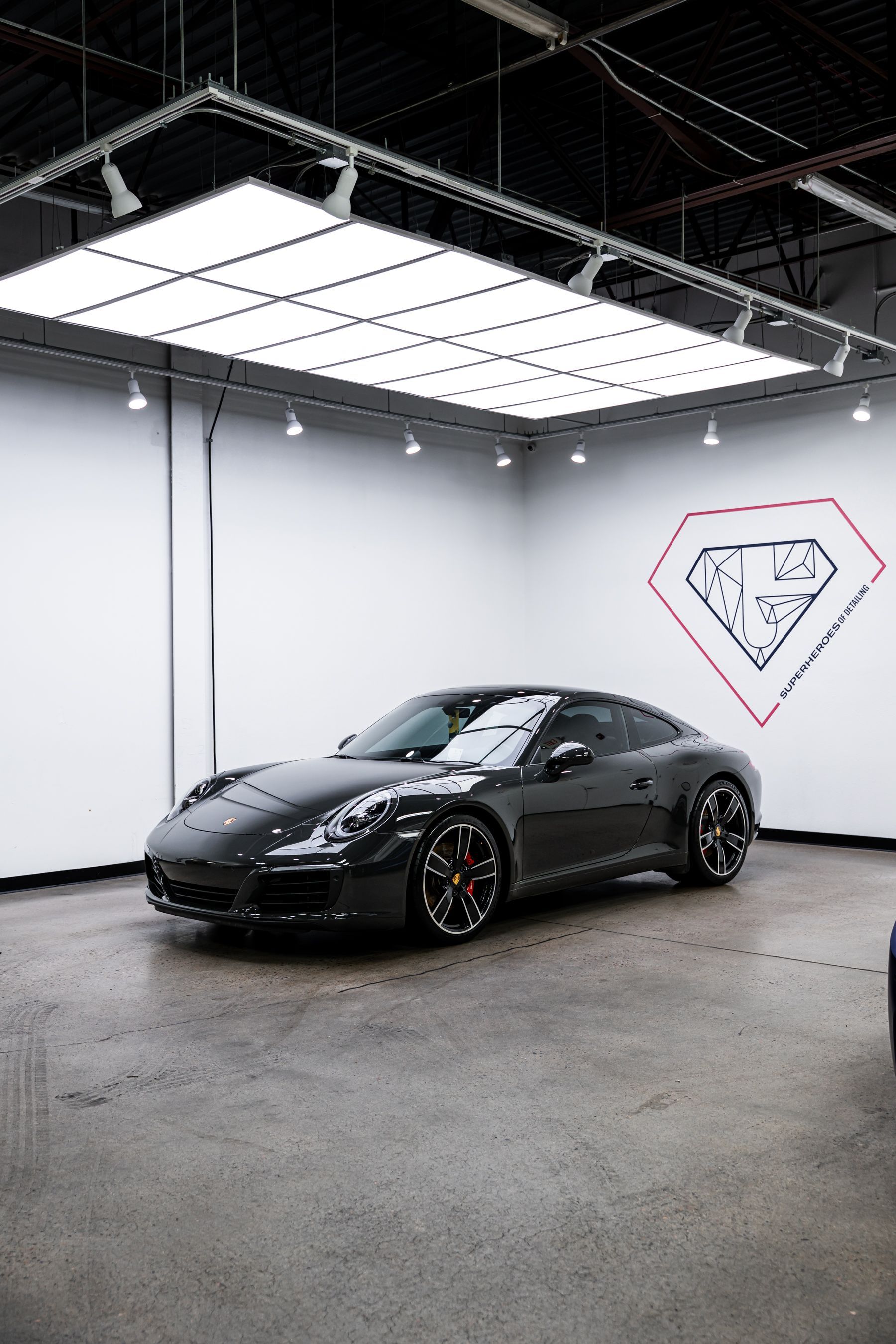 A black porsche 911 is parked in a showroom.