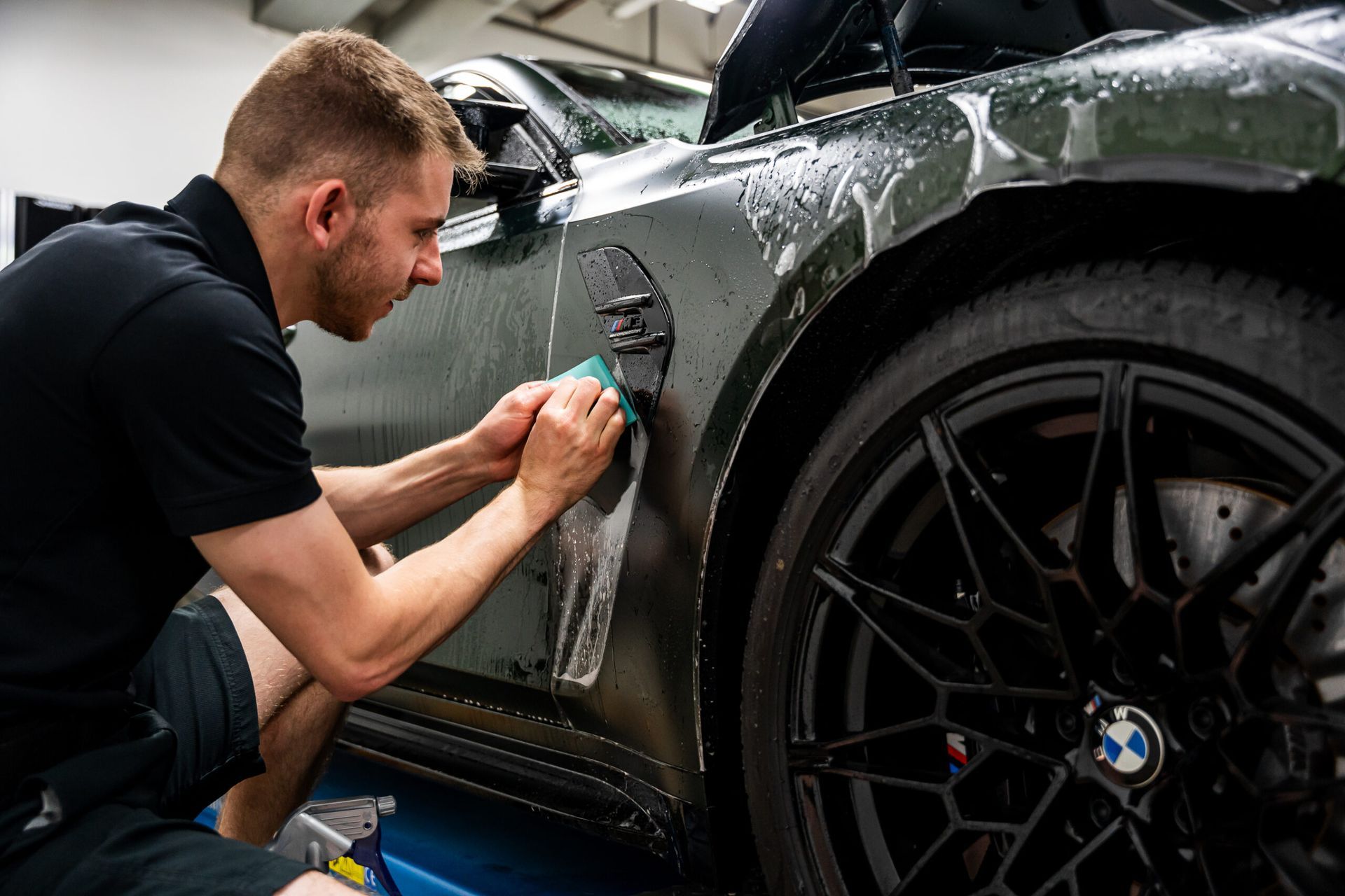 A man is cleaning the side of a car with a sponge.