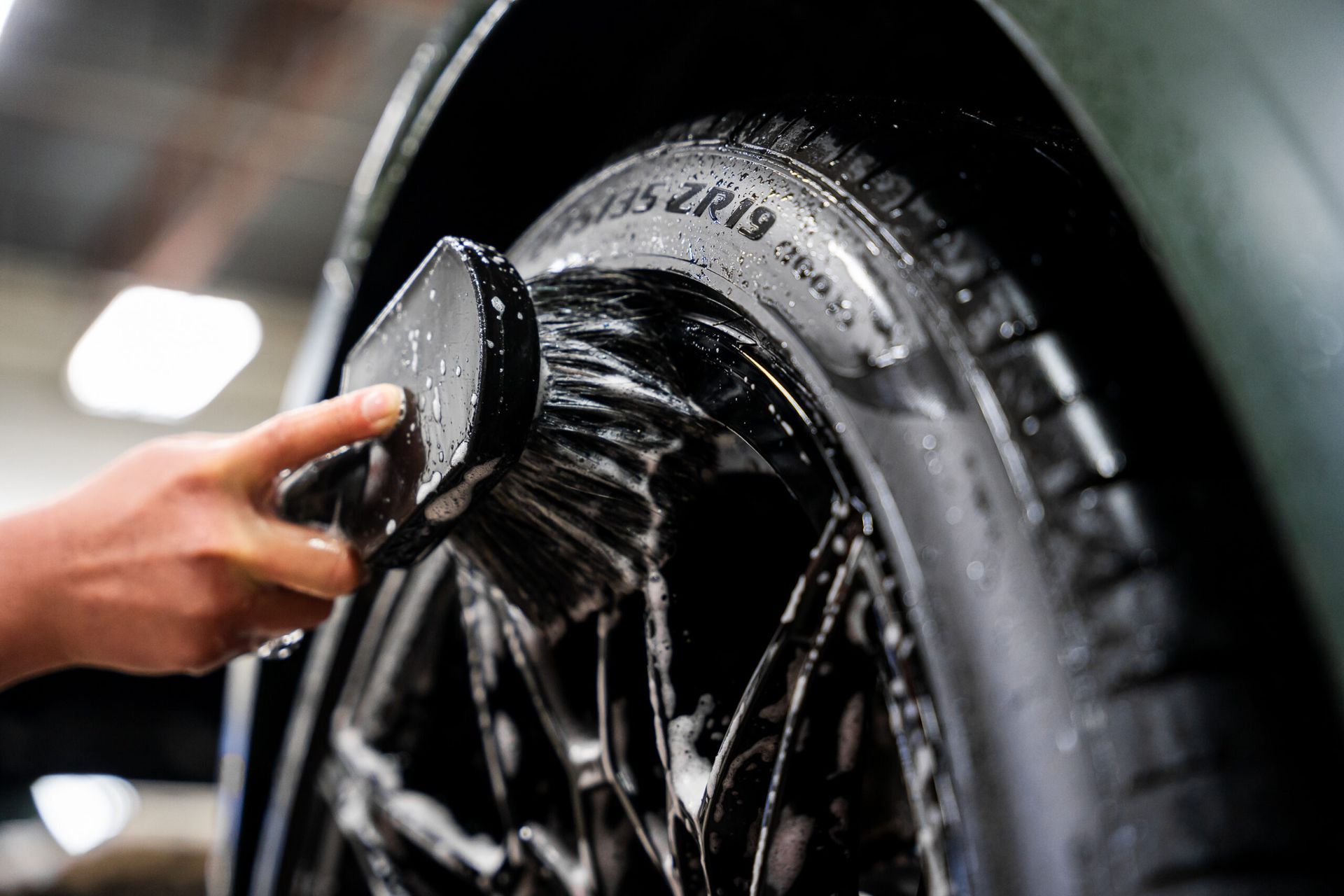 A person is cleaning a tire with a sponge.