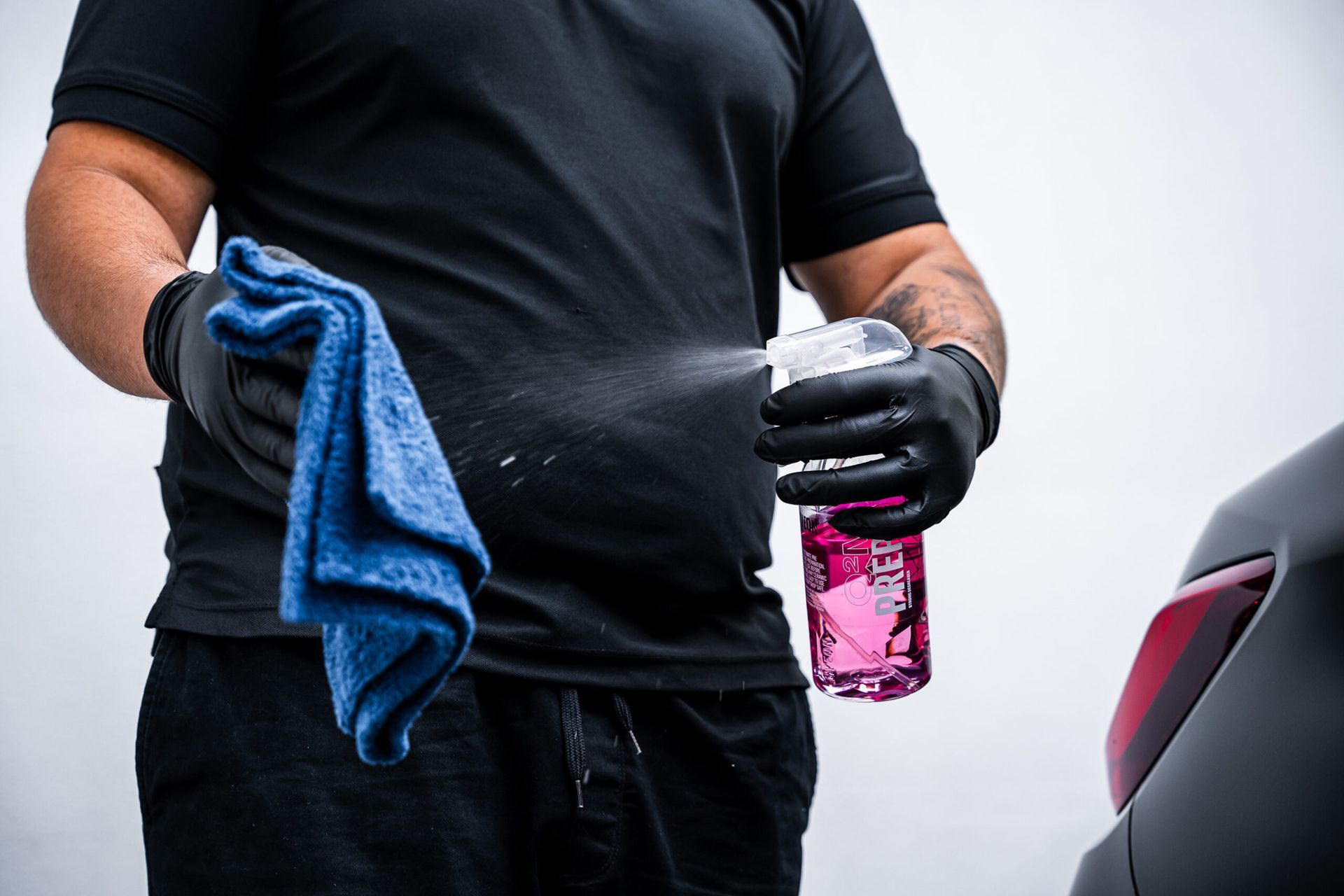 A man is holding a spray bottle and a blue towel.