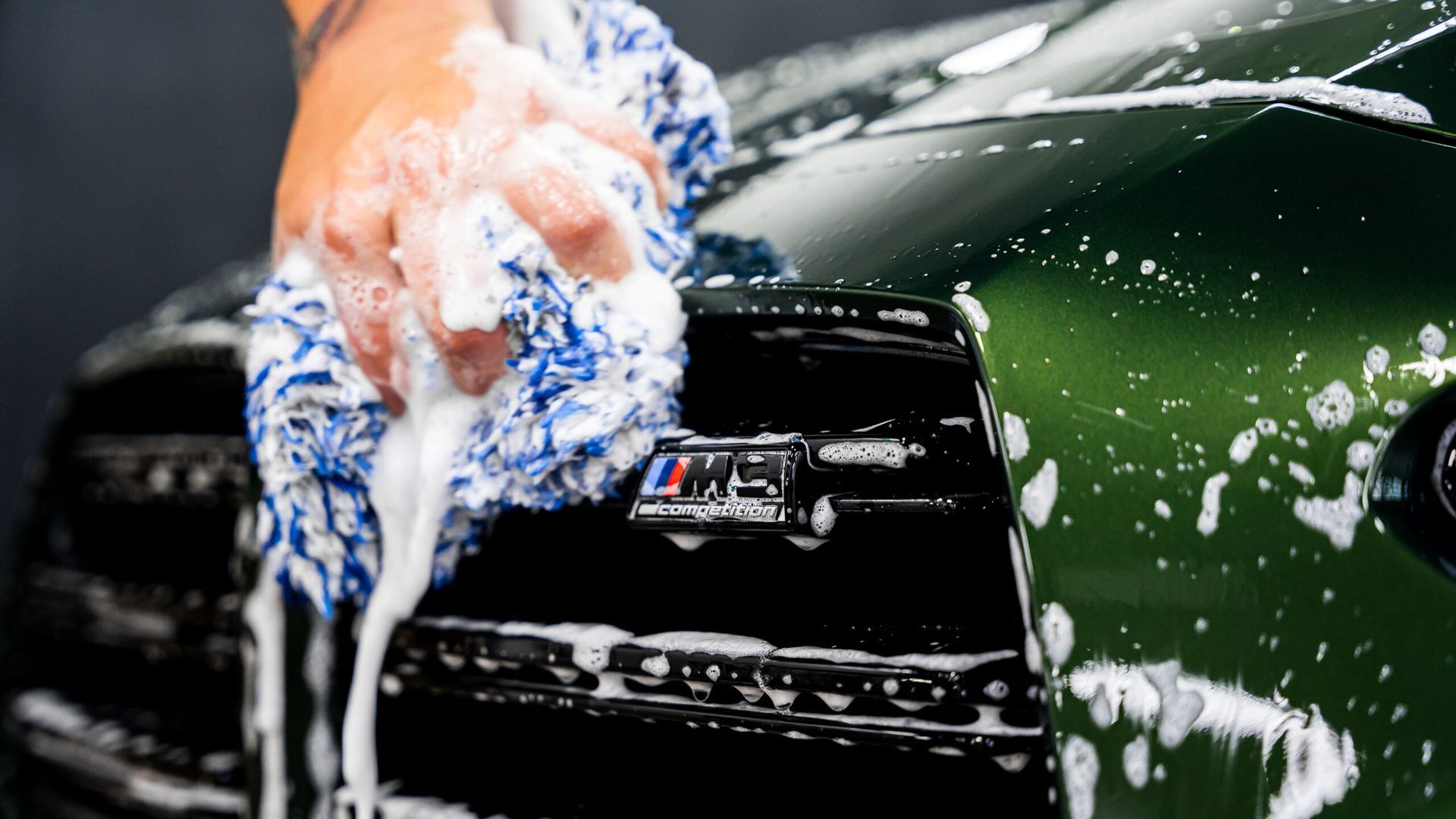 A person is washing a car with a towel and soap.