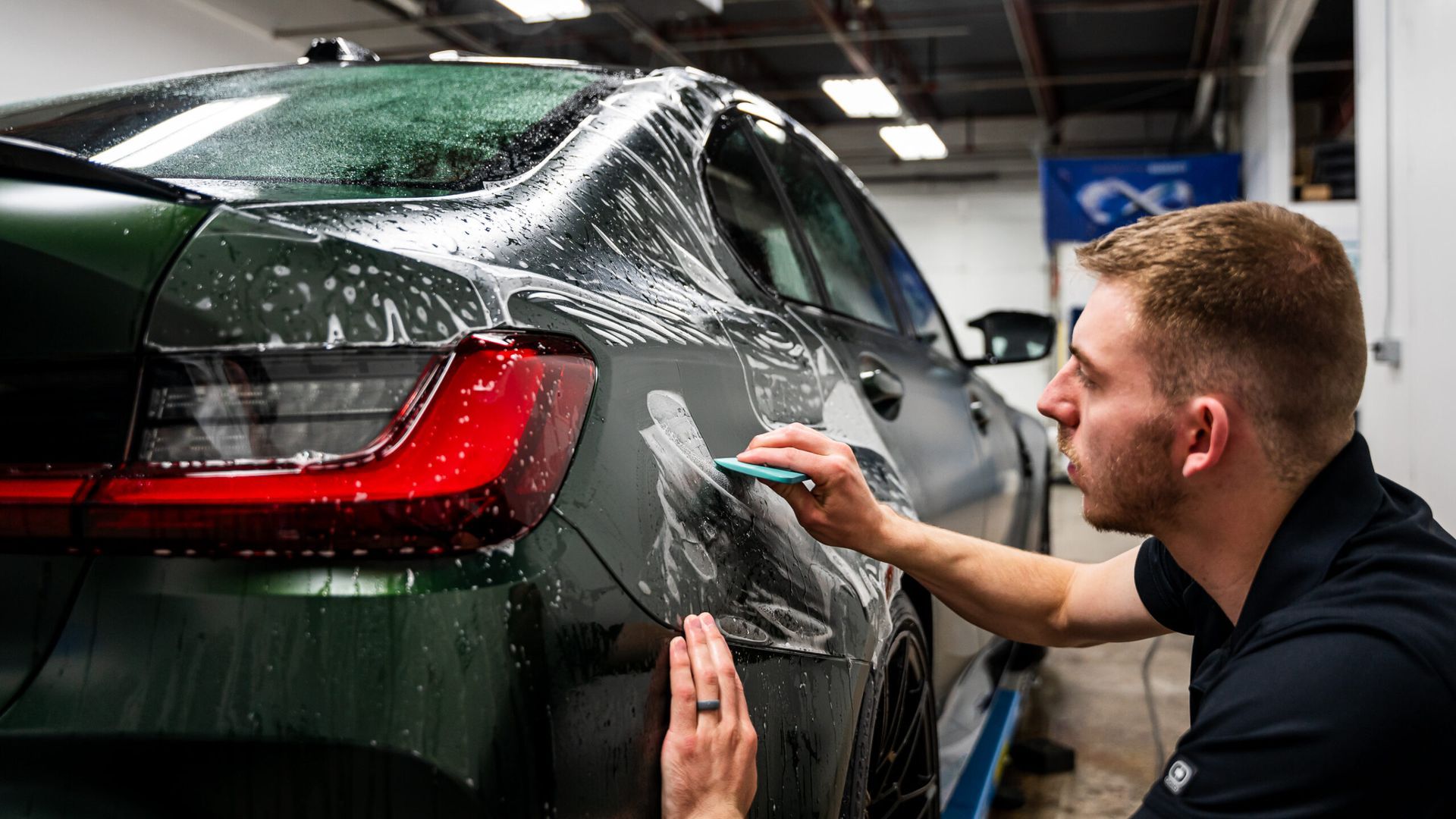 A man is wrapping a car with a sponge in a garage.