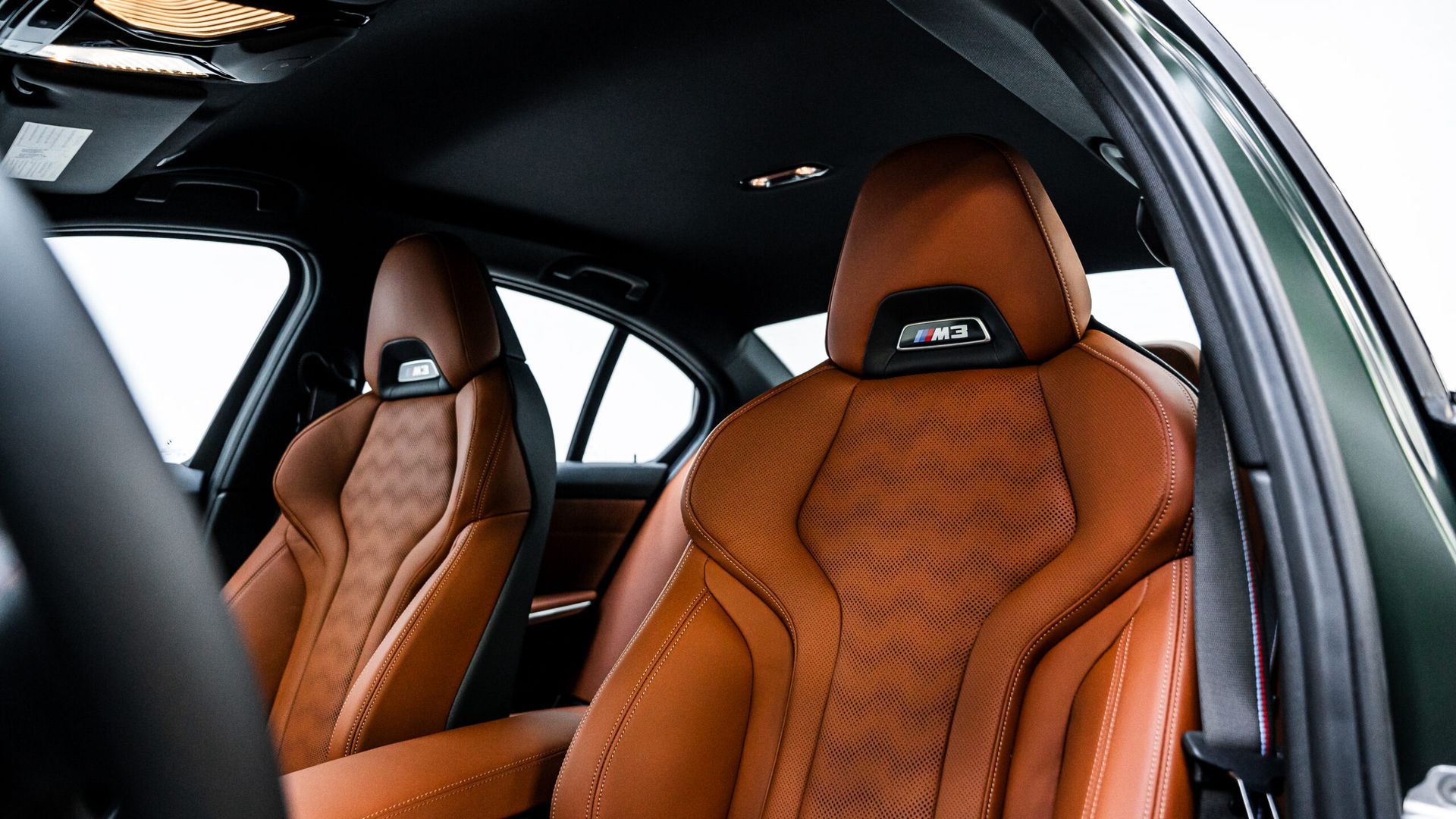 The interior of a car with brown leather seats and a black steering wheel.