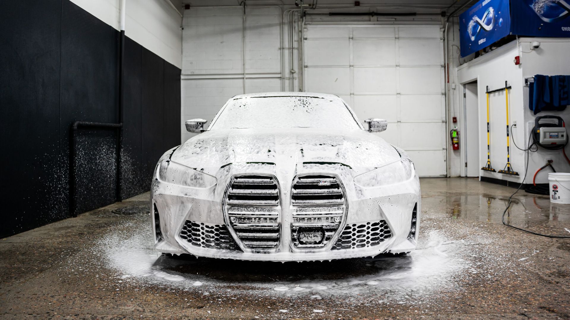 A car is covered in foam in a garage.