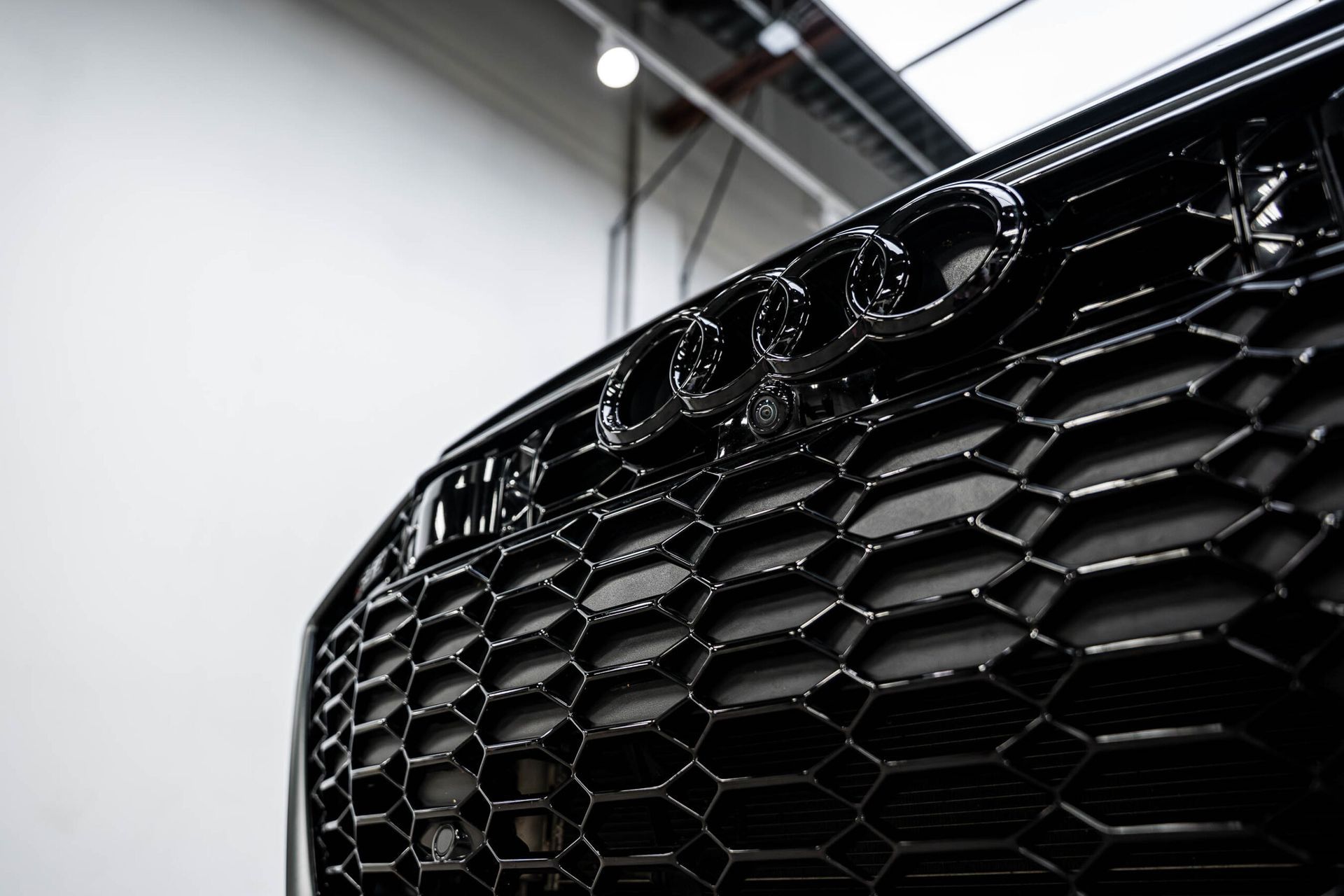 A close up of a black car 's grille in a garage.