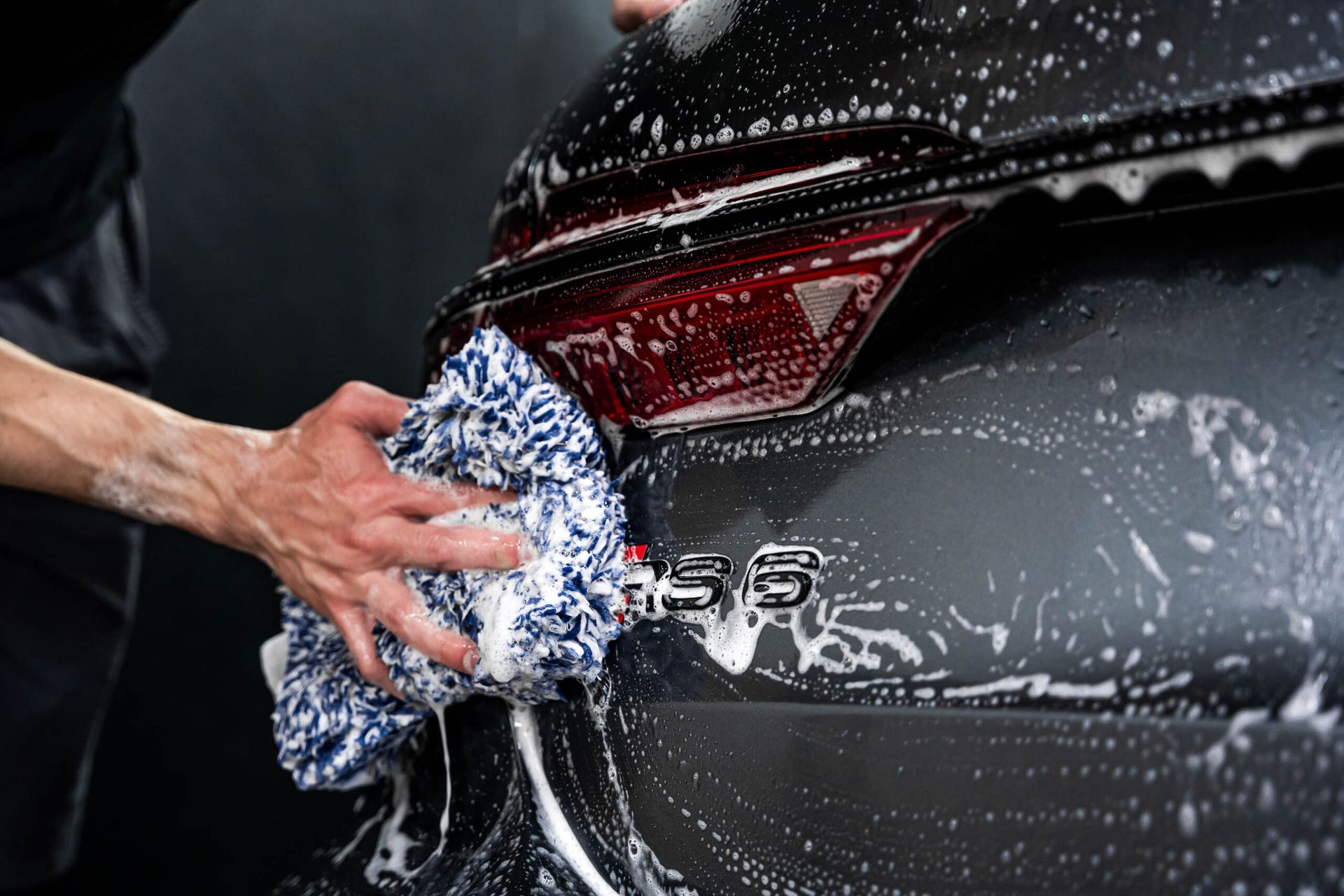 A person is washing a car with a towel and soap.