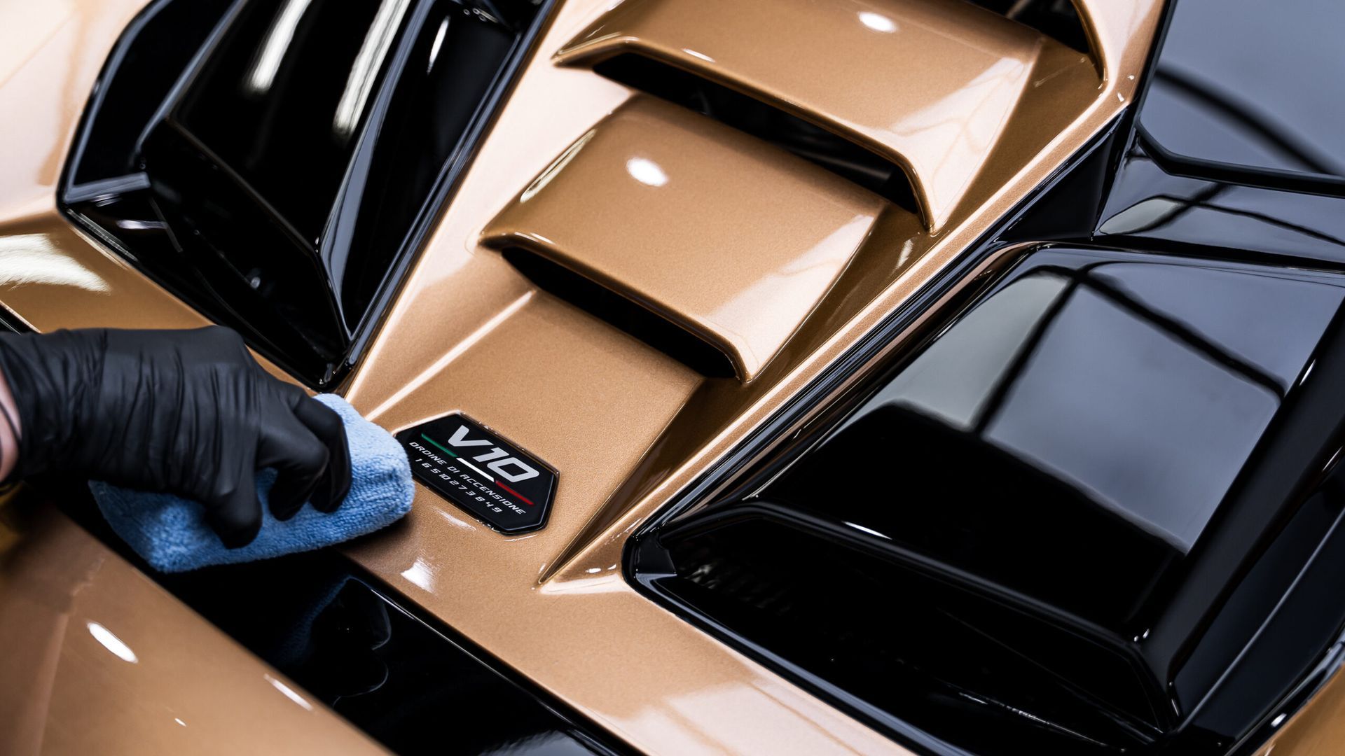 A person is cleaning the hood of a car with a cloth.