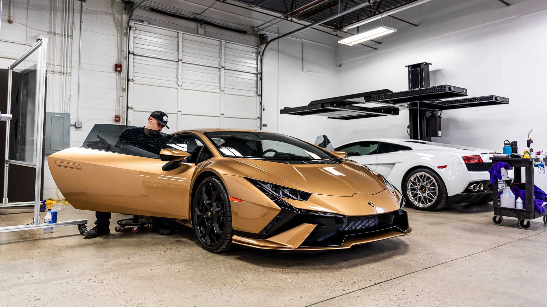 A man is working on a gold lamborghini in a garage.