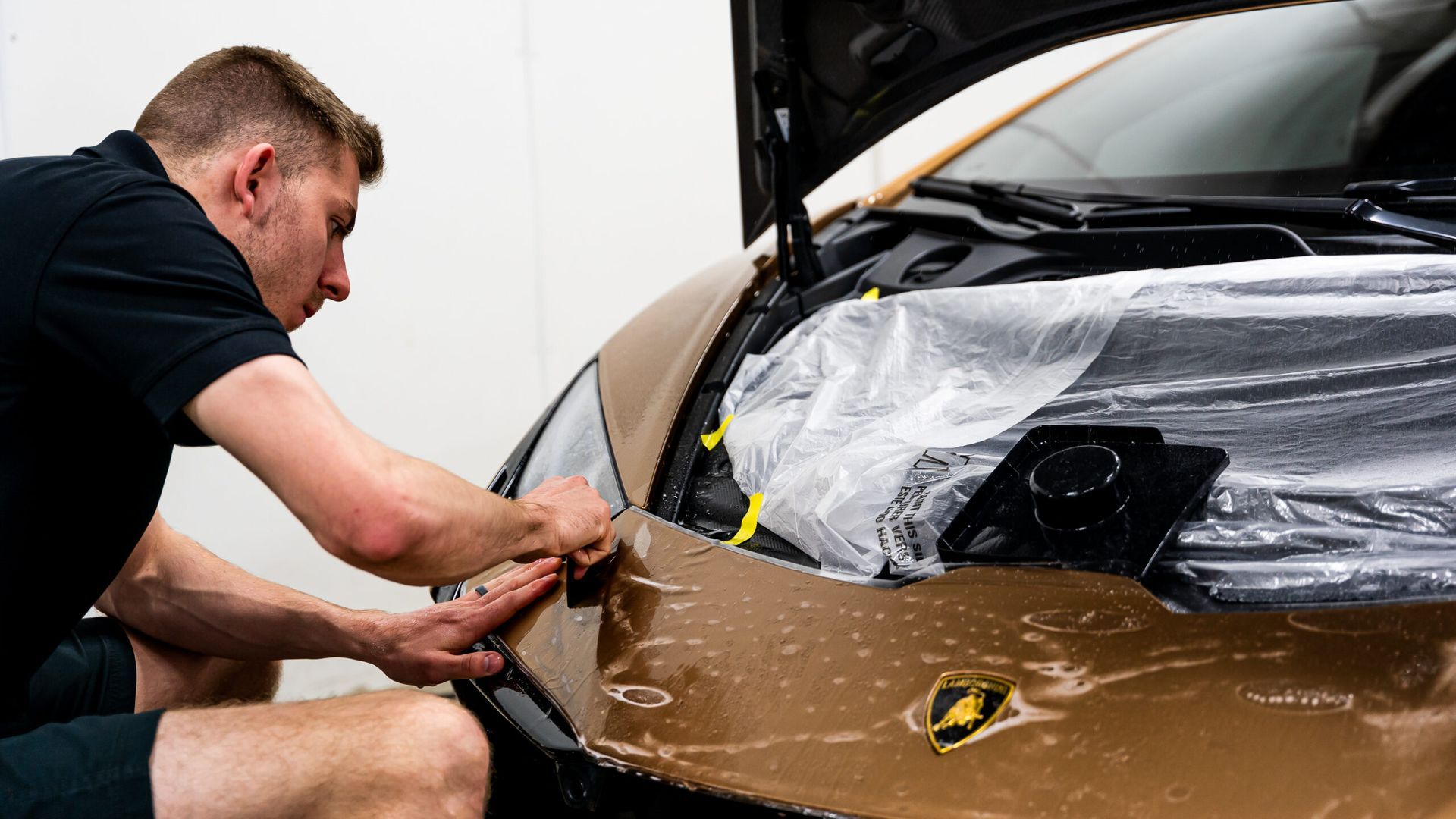 A man is wrapping a car with plastic wrap.