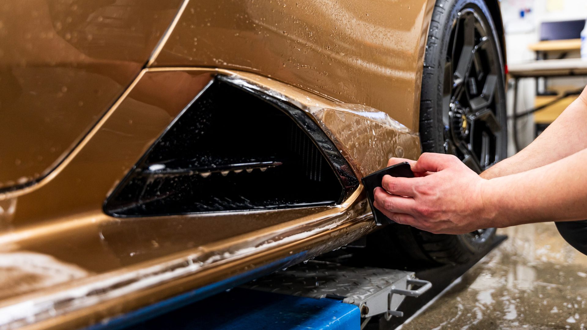 A person is applying a protective film to the side of a car.