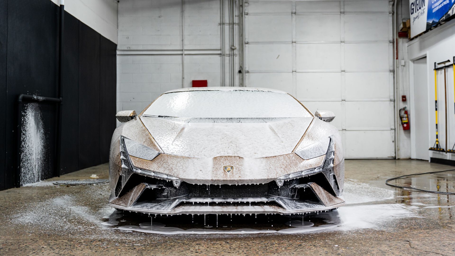 A lamborghini huracan is covered in foam in a garage.