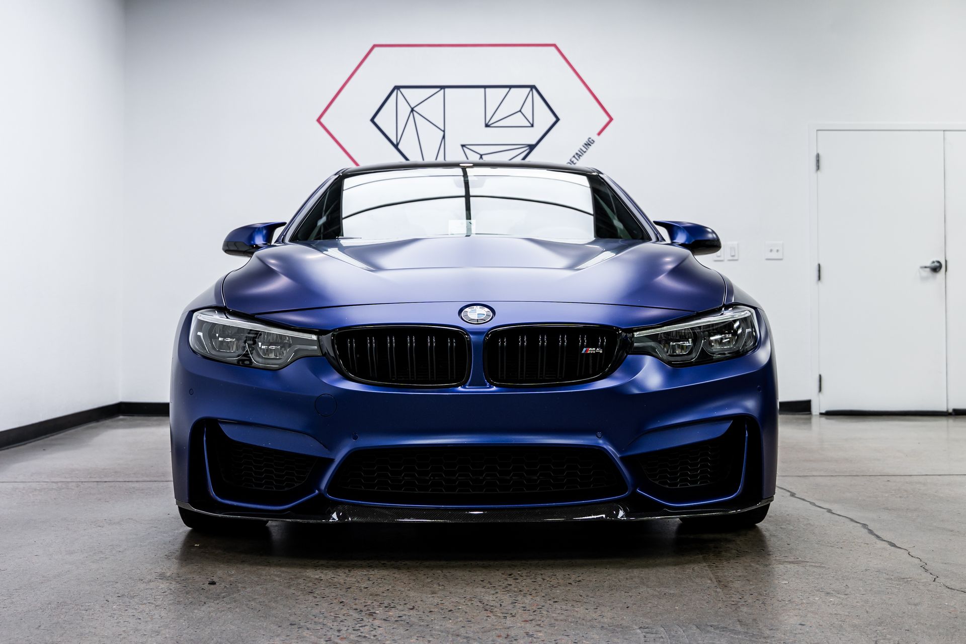 A blue bmw m4 convertible is parked in a garage.