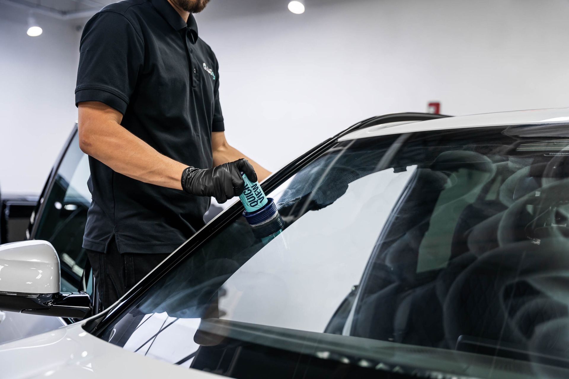 A man is polishing the windshield of a car.