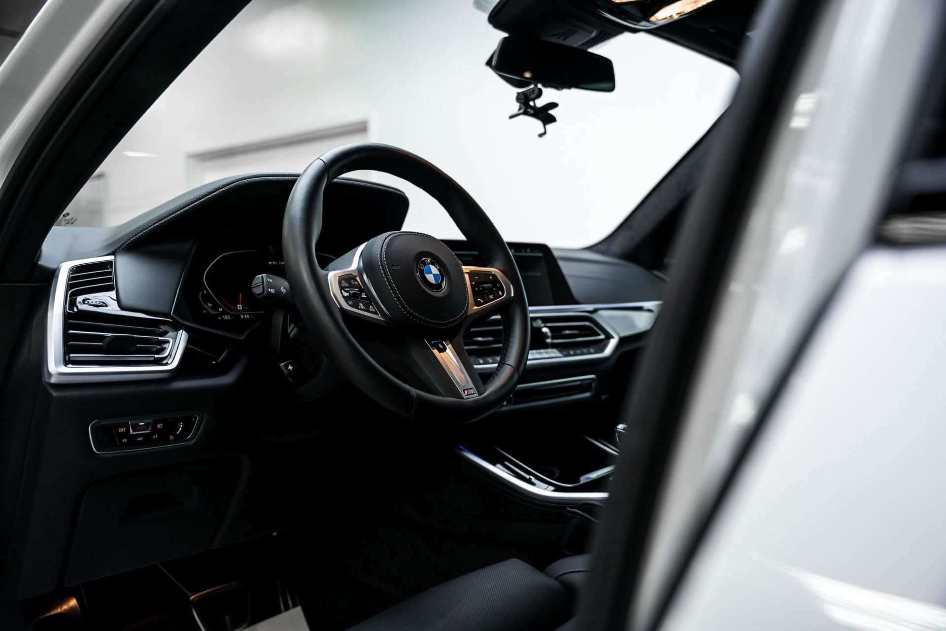 The interior of a bmw x5 with the door open and the steering wheel visible.