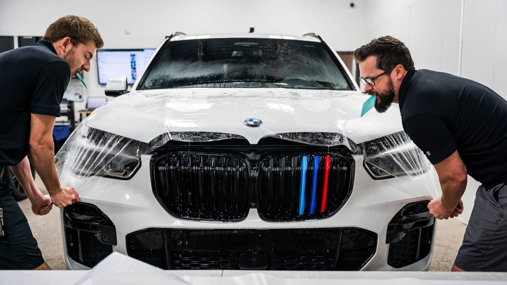 Two men are working on a white bmw x5.